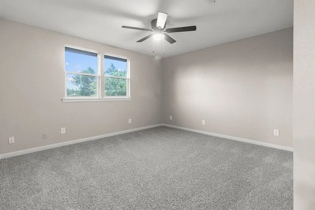 Neutral tone wall paint, gray carpeting, dual pane windows, and a ceiling fan with integrated lighting
