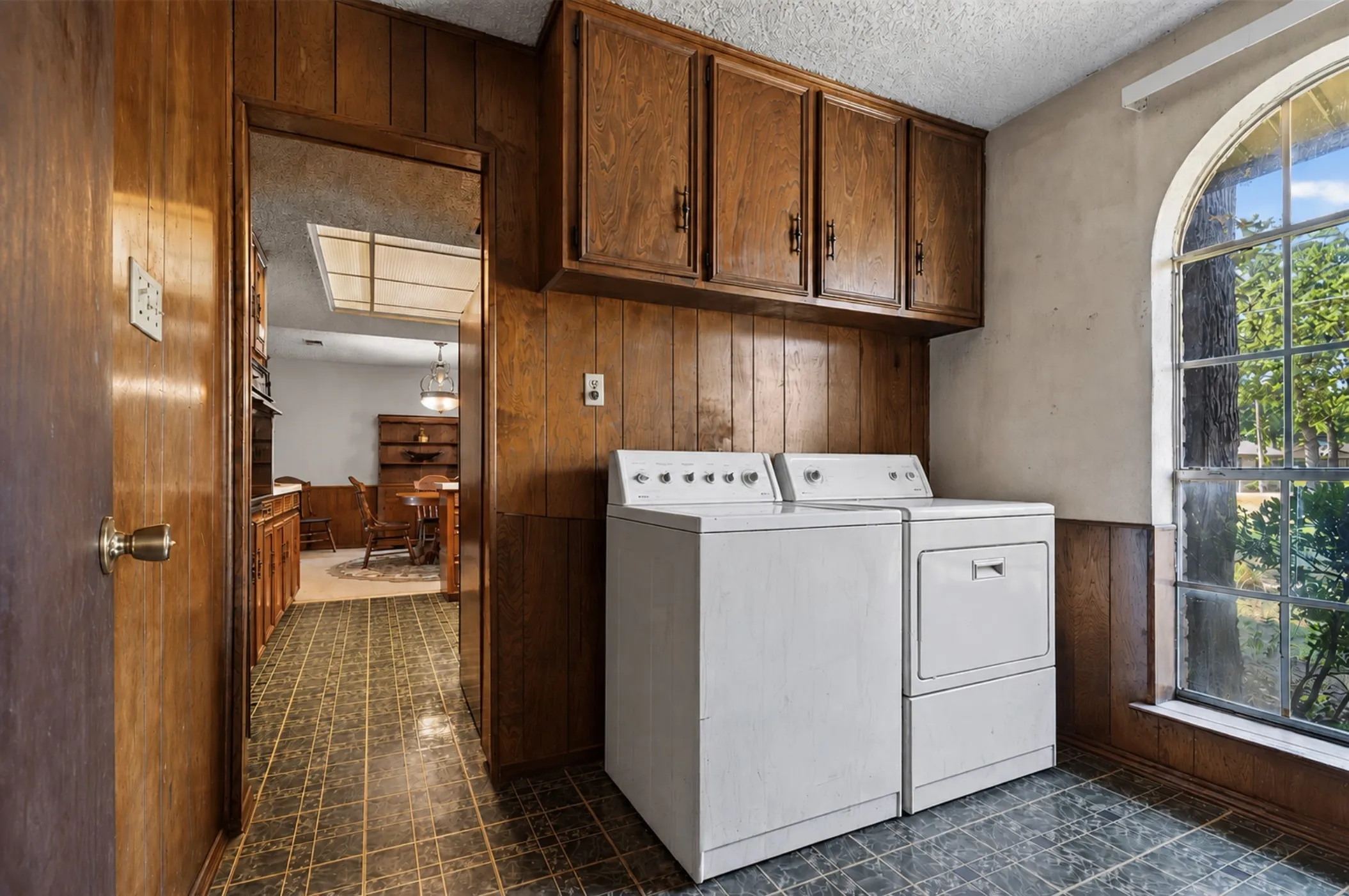 Wood paneling throughout, built-in upper cabinetry, and an arched window
