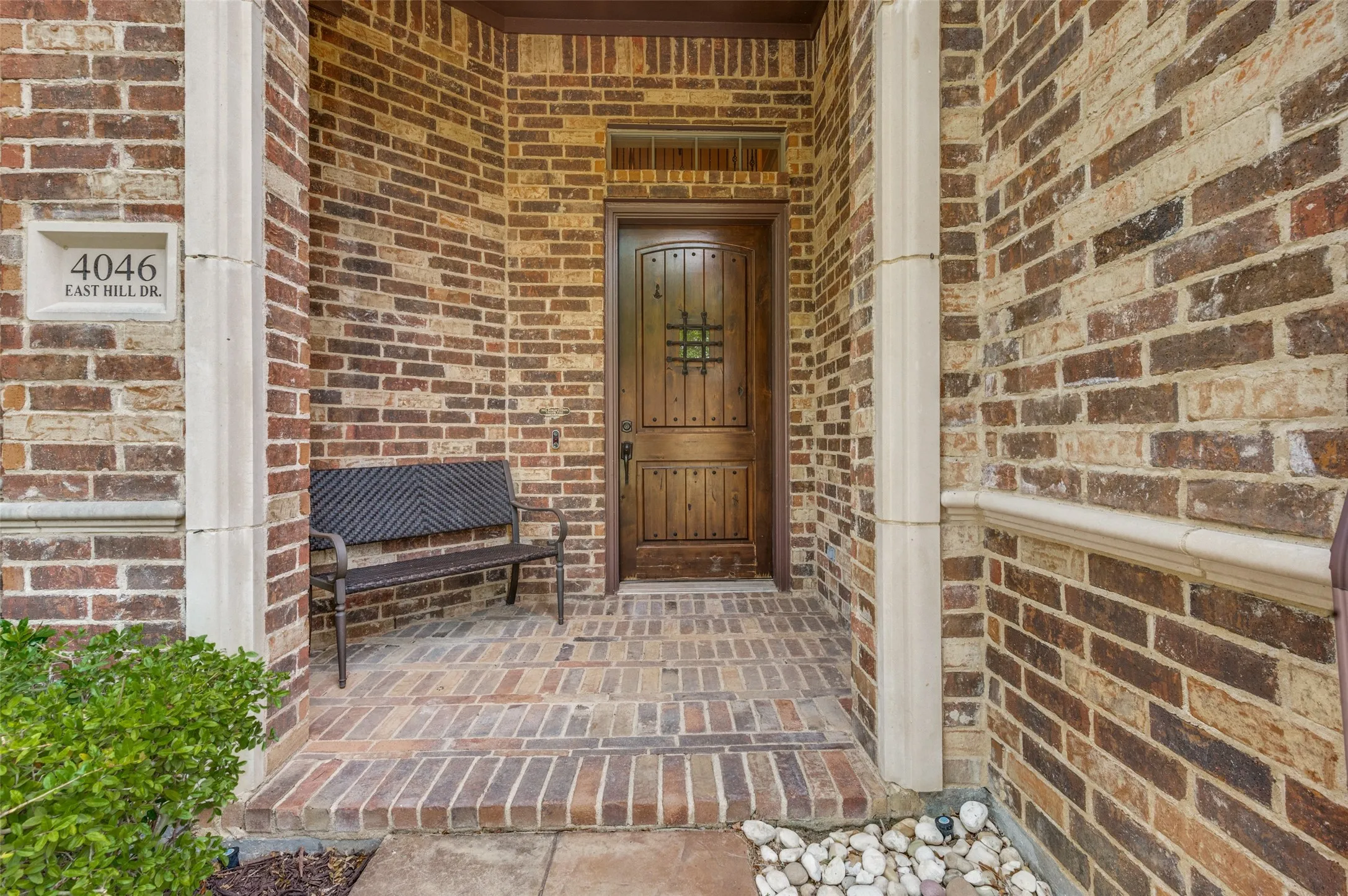 Brick exterior with stone accents, wood entry door, and a brick-patterned porch