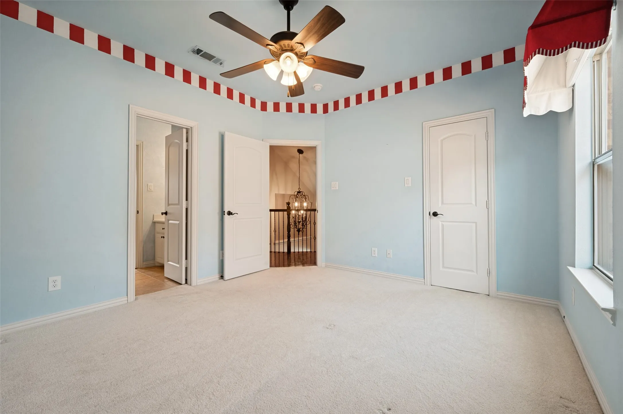 Light-colored carpeting, blue-painted walls, and a ceiling fan with integrated lighting