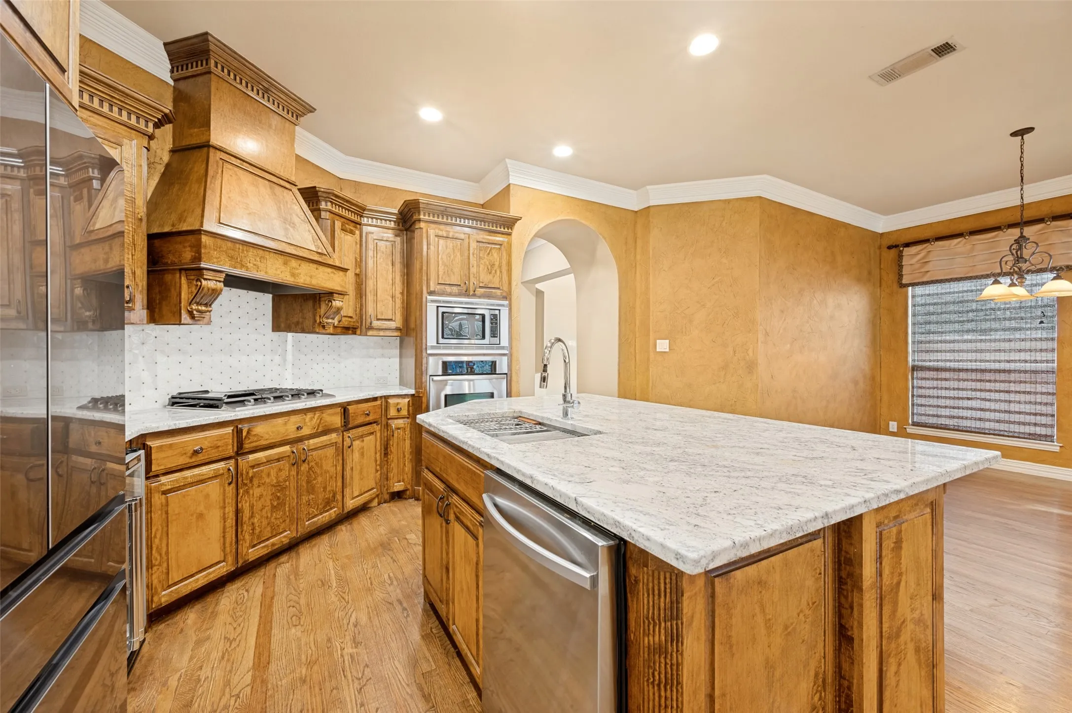 Kitchen featuring wood cabinetry, light-toned countertops, stainless steel appliances, and wood-finish flooring