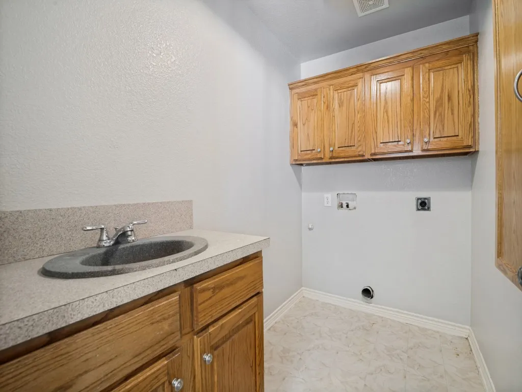 Utility area featuring wood cabinetry, laminate countertop, and a built-in sink