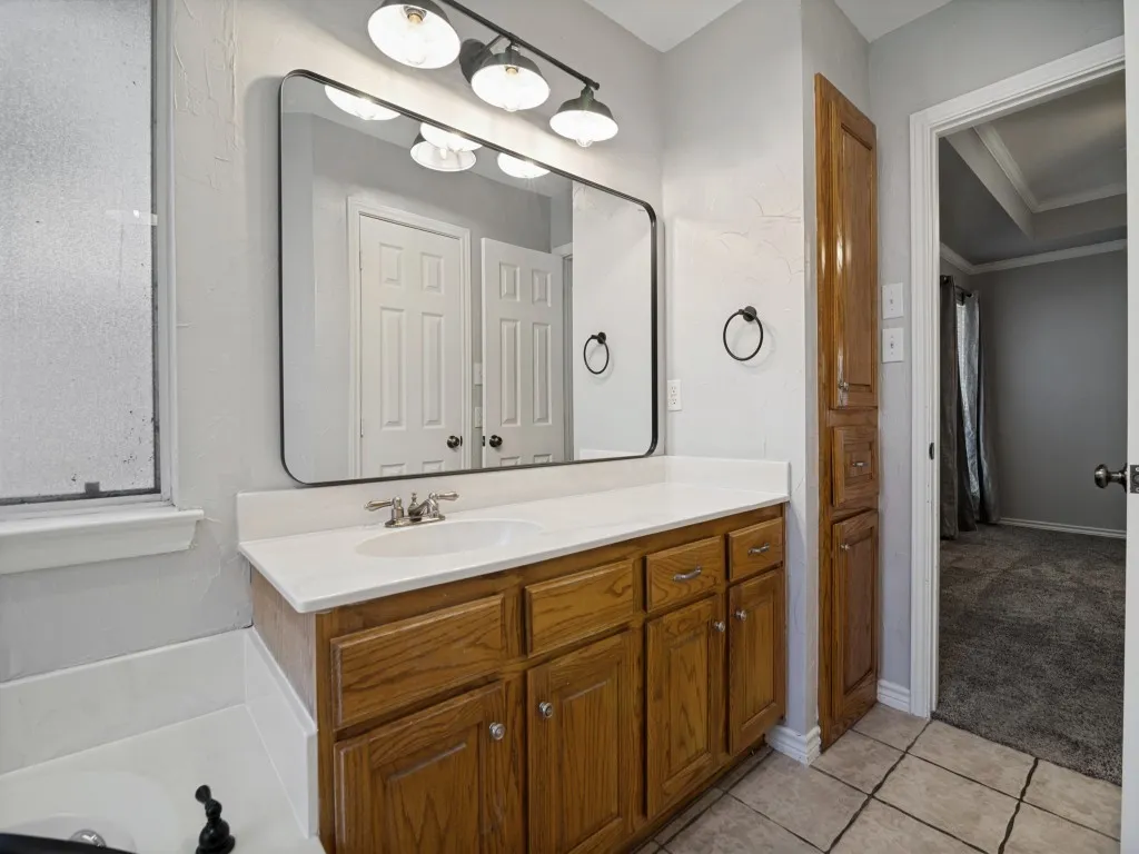 Vanity with white countertop, integrated sink, and wood-finish cabinetry