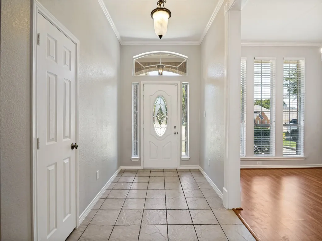 Entryway with ceramic tile flooring, a decorative glass front door, transom window, and a chandelier