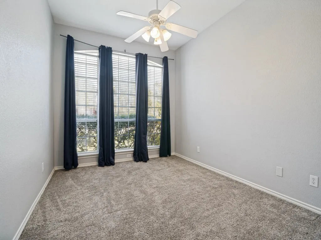 Vaulted ceiling with a ceiling fan, three pane windows, and light gray textured walls