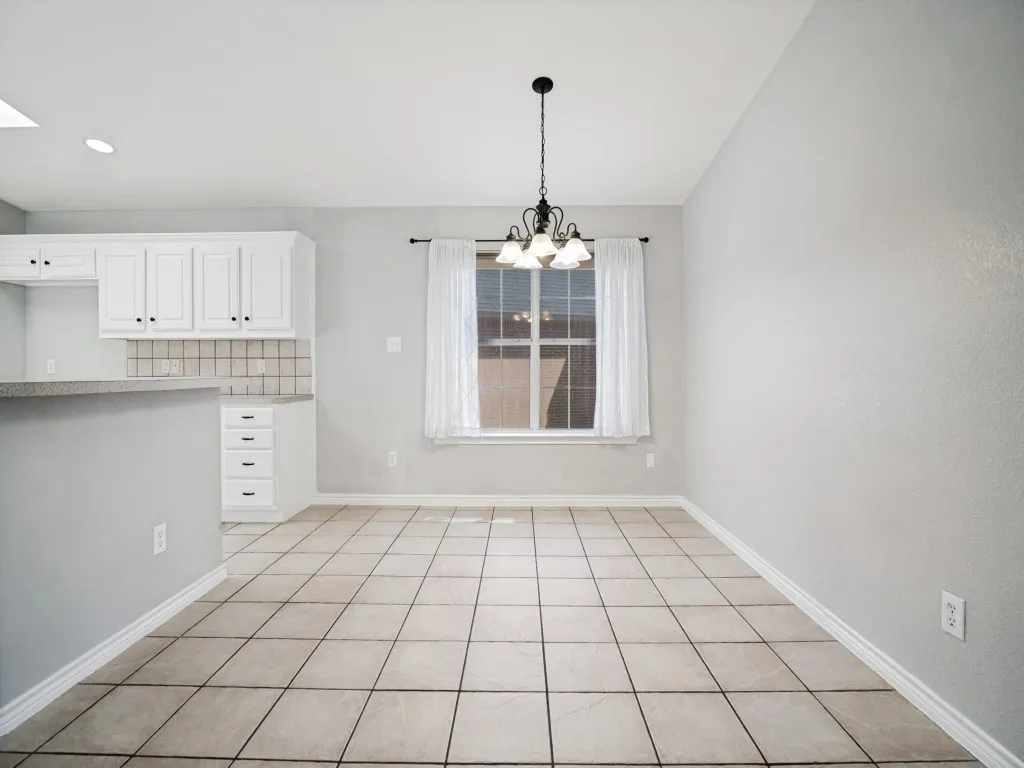 Recessed lighting, tile flooring, window with natural light, white cabinetry, and a black chandelier