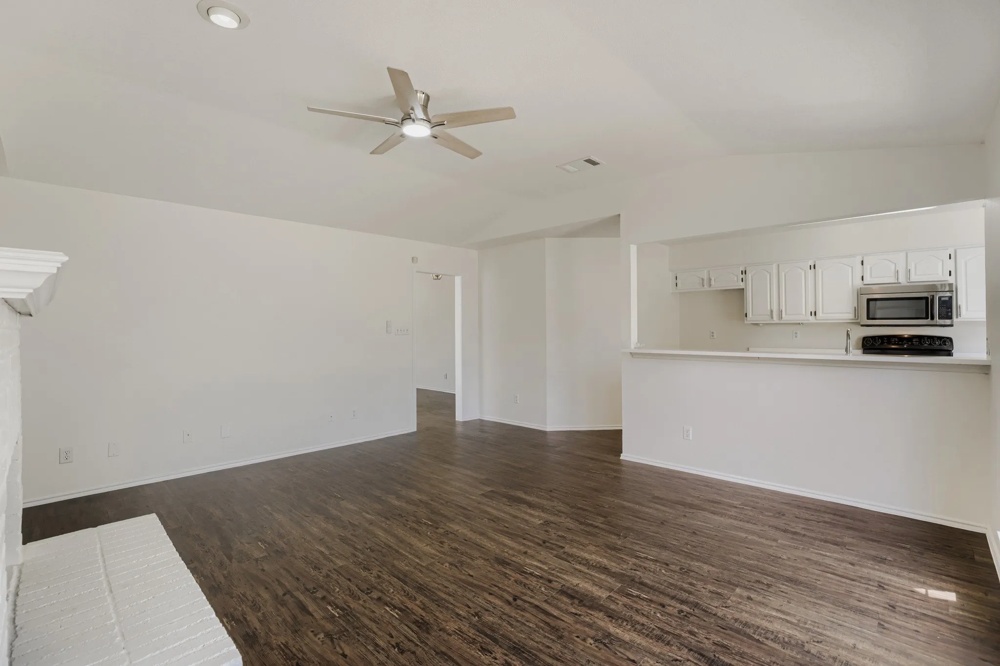 Wood-finish flooring throughout, vaulted ceiling with recessed lighting, and a ceiling fan