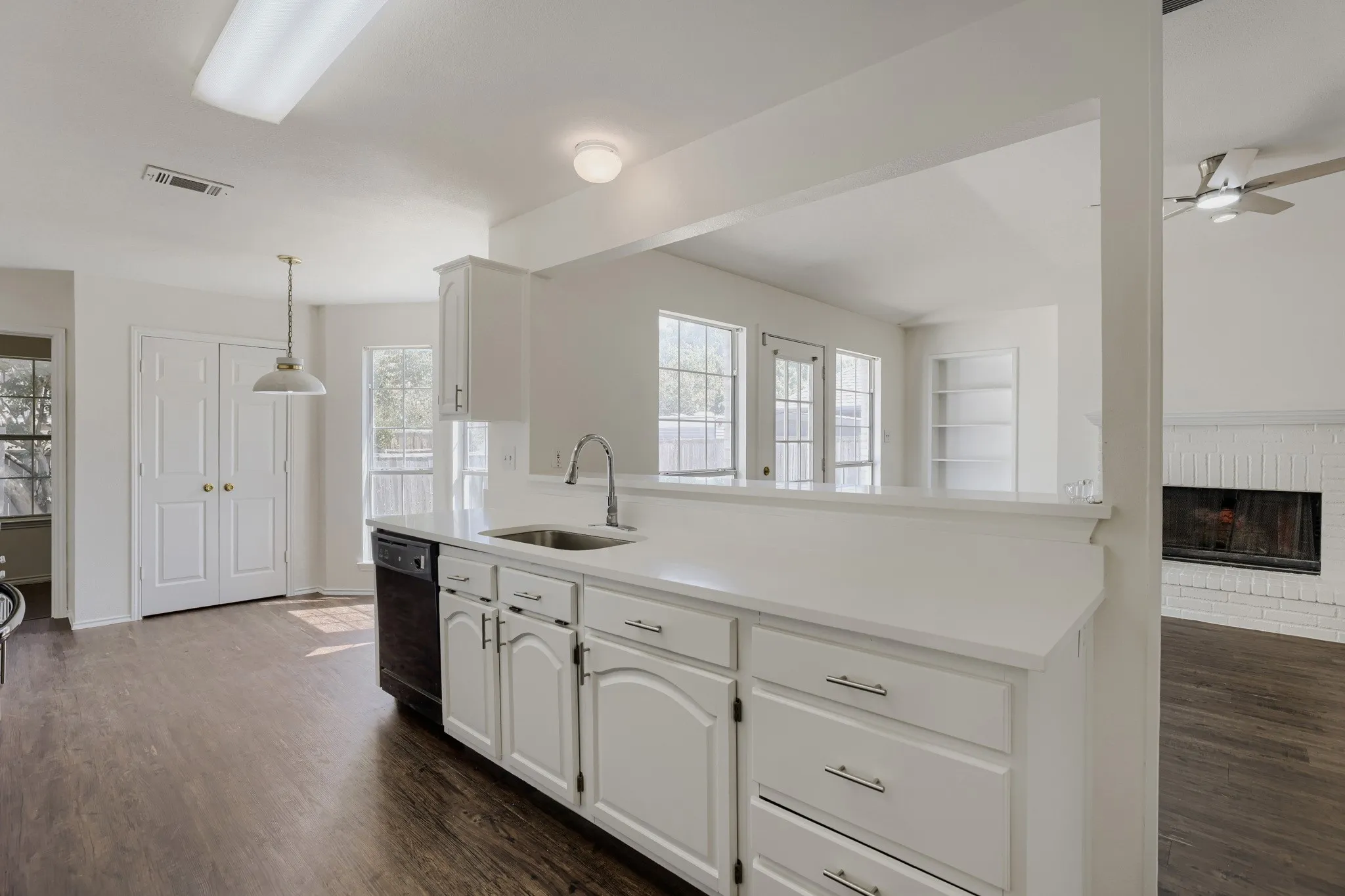 Kitchen featuring white cabinetry, a stainless steel sink, and wood-finish flooring
