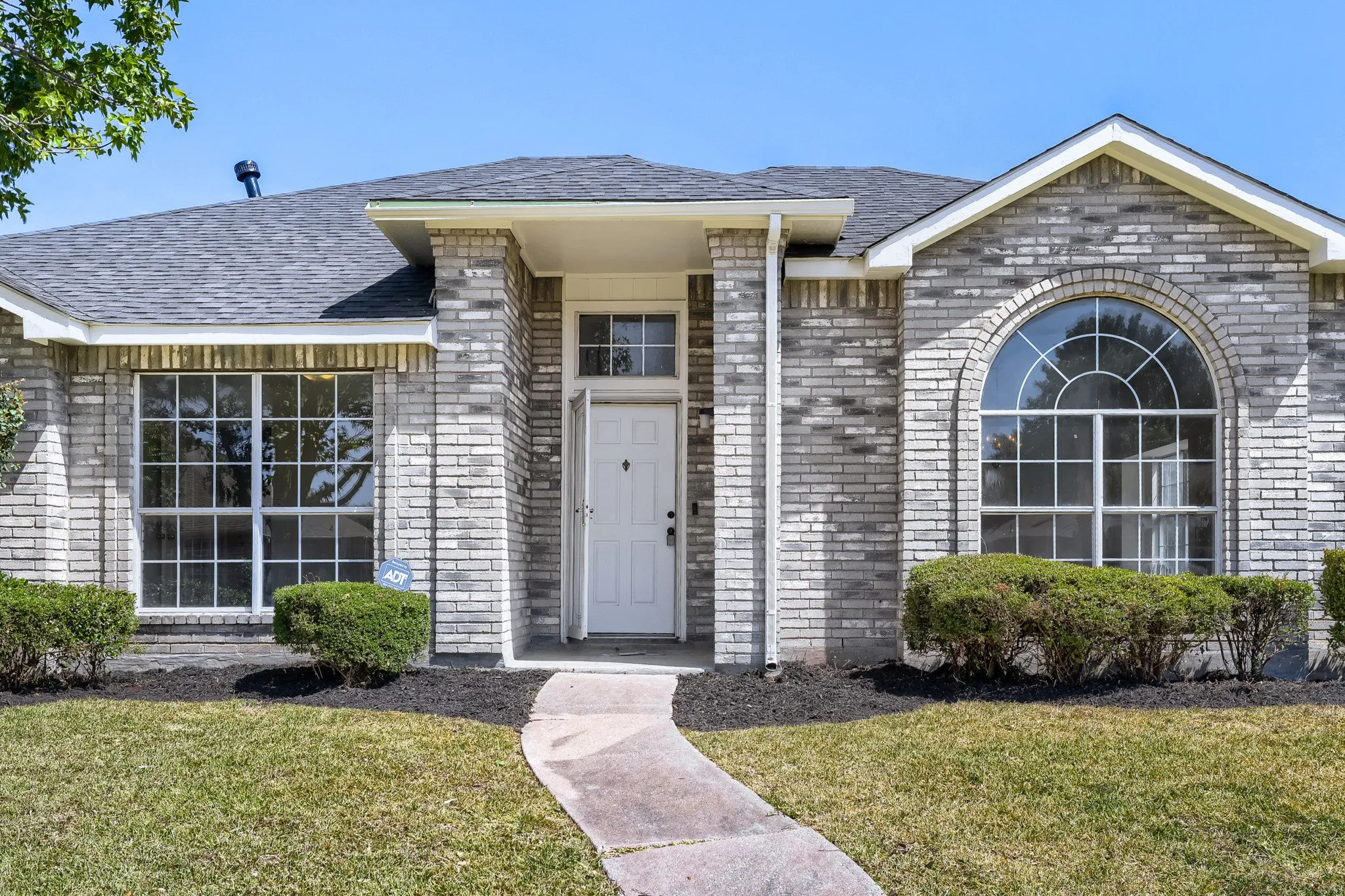 Brick facade with a gabled roof and arched window