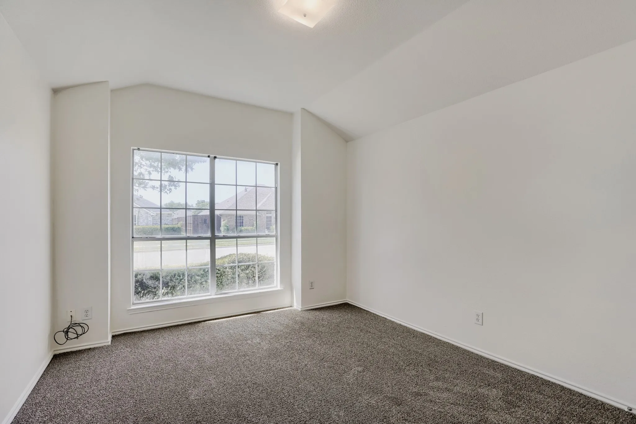 Vaulted ceiling, gridded window, neutral carpeting, recessed lighting, and crisp white walls