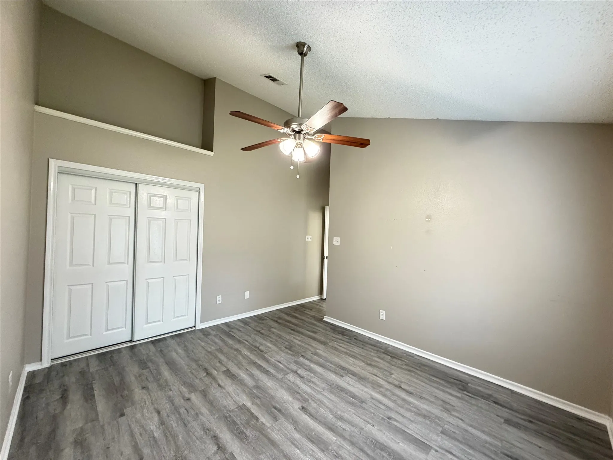 Vaulted ceiling with a ceiling fan, wood-finish flooring, and white trim