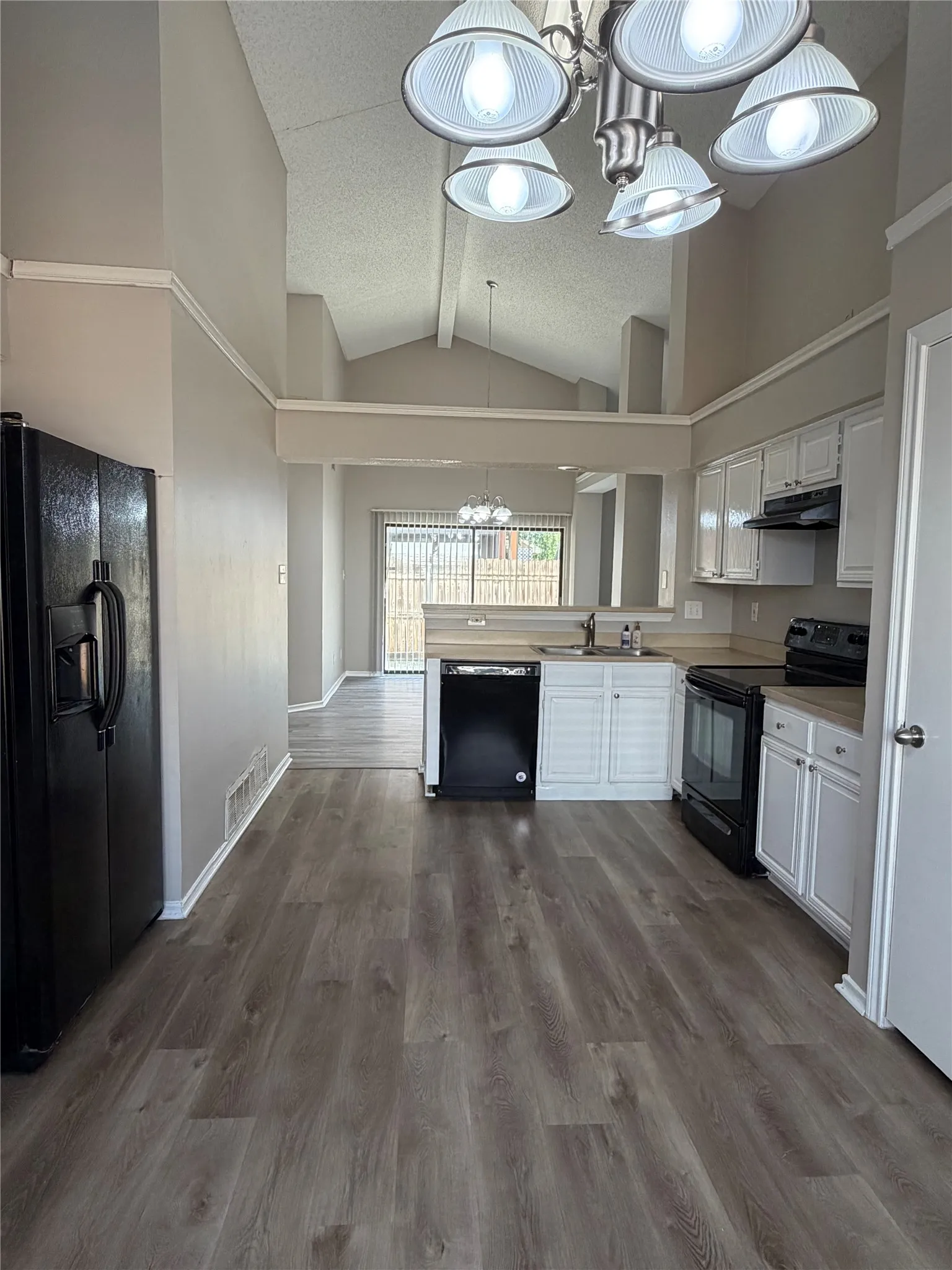 Kitchen featuring wood-finish flooring, white cabinetry, a black appliance suite, and a brushed nickel chandelier