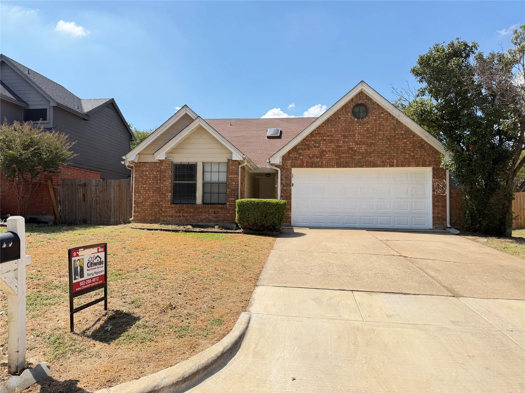 Brick exterior with a peaked roofline, attached garage, and mature landscaping