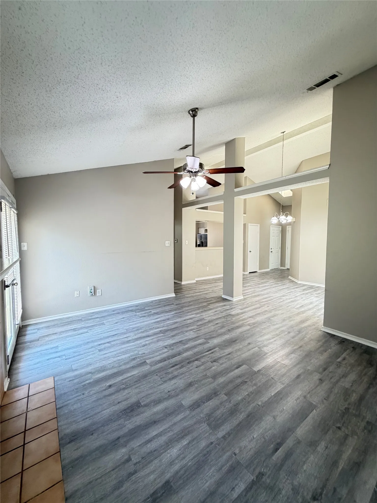 Vaulted ceilings, wood-finish flooring, ceiling fan with integrated lighting, and a tiled hearth