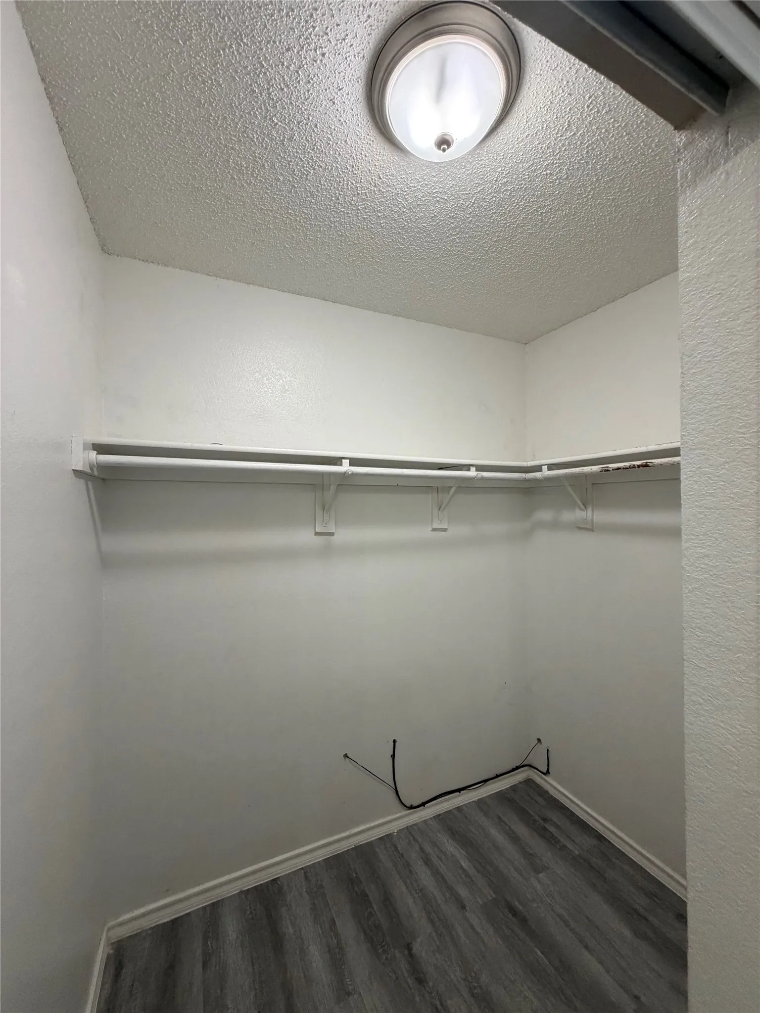 Recessed lighting fixture, textured ceiling, built-in shelving, and wood-finish flooring