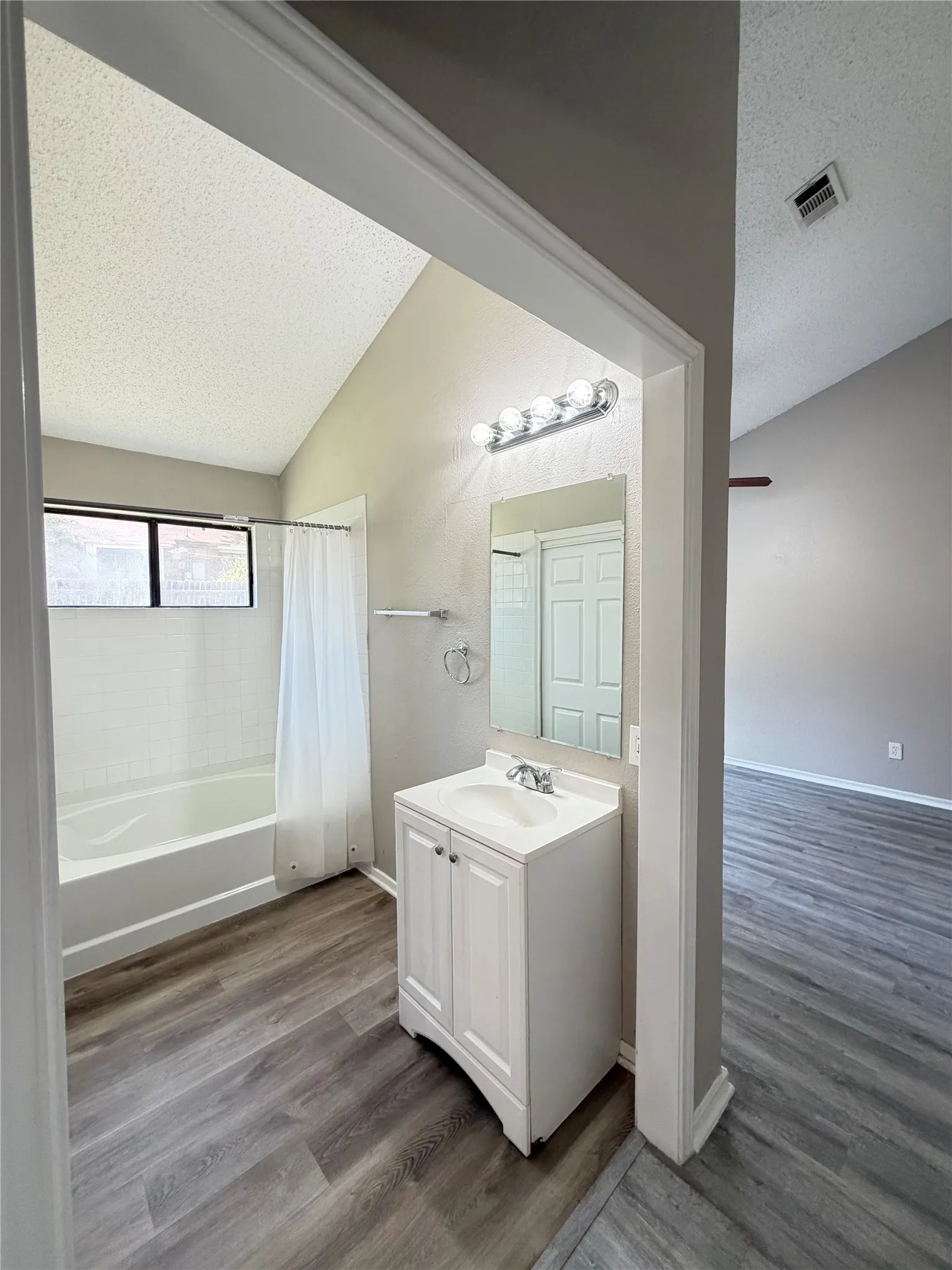Bathroom featuring a white vanity with integrated sink, chrome fixtures, and a bathtub with a tiled surround