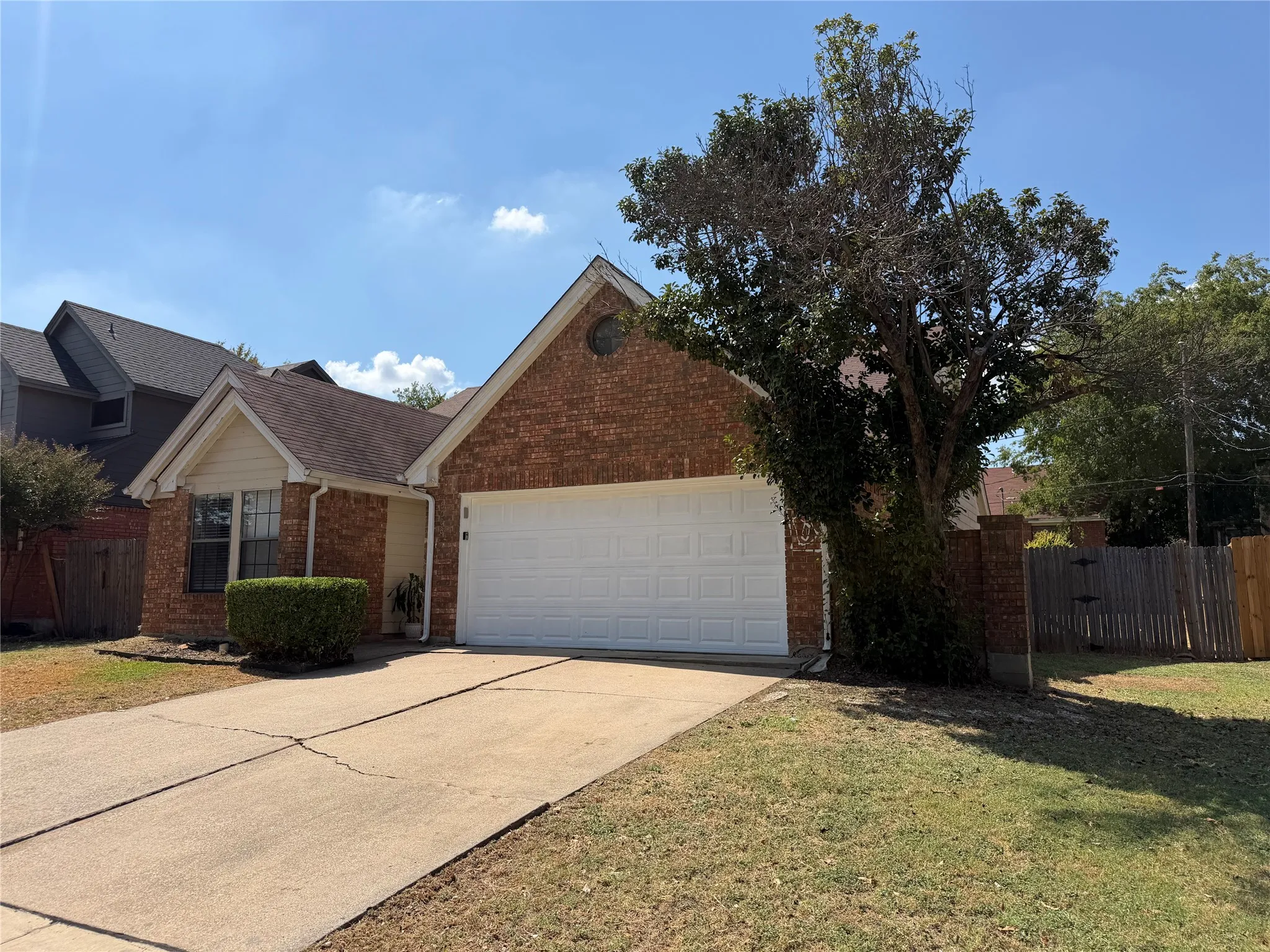 Brick exterior with a peaked roofline, attached garage, and concrete driveway