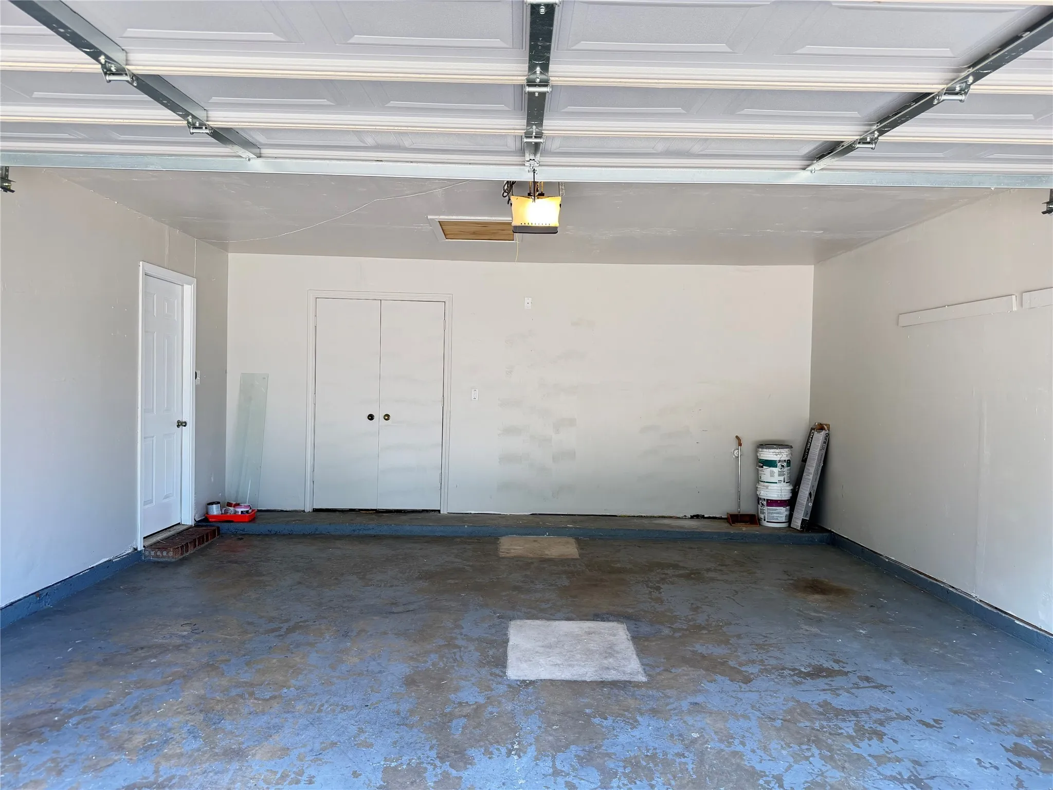 Attached garage with a panel garage door, interior access door, and a double-door storage closet