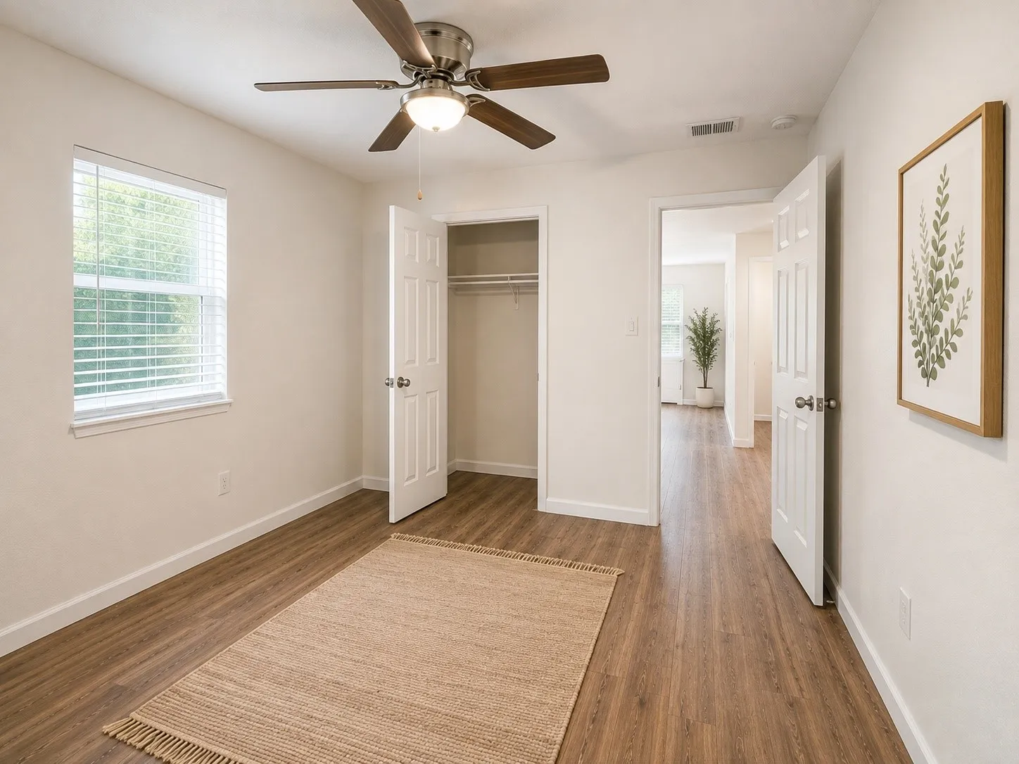 Wood-finish flooring throughout, bright window with blinds, ceiling fan with integrated lighting, and a closet with bifold doors