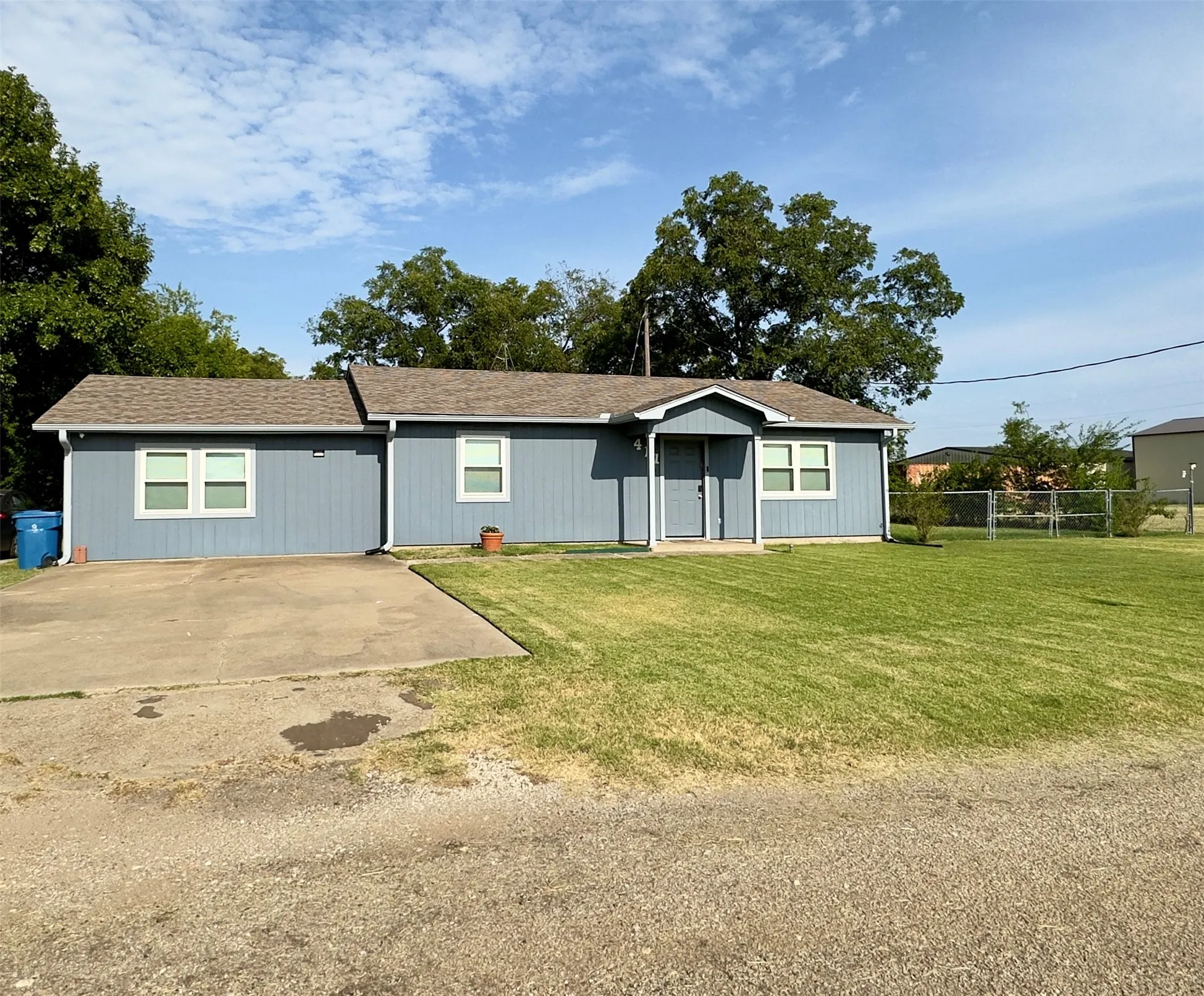 Single-story residence featuring light blue siding, a brown shingle roof, white trim windows, and a concrete driveway