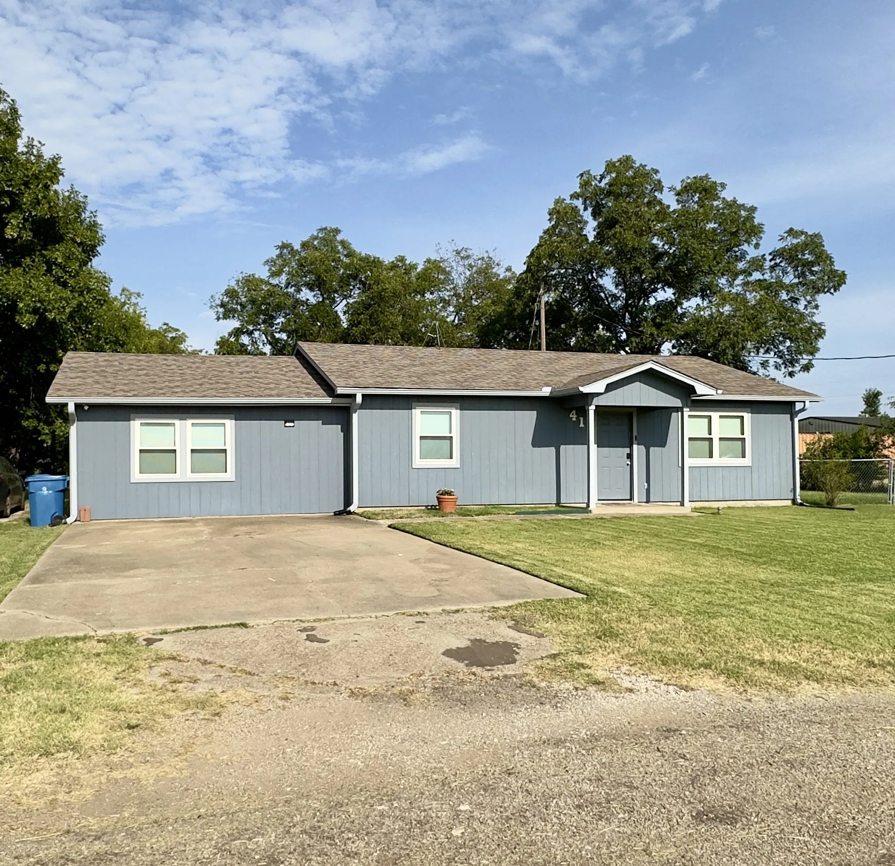 Single-story residence featuring blue siding and a brown shingle roof