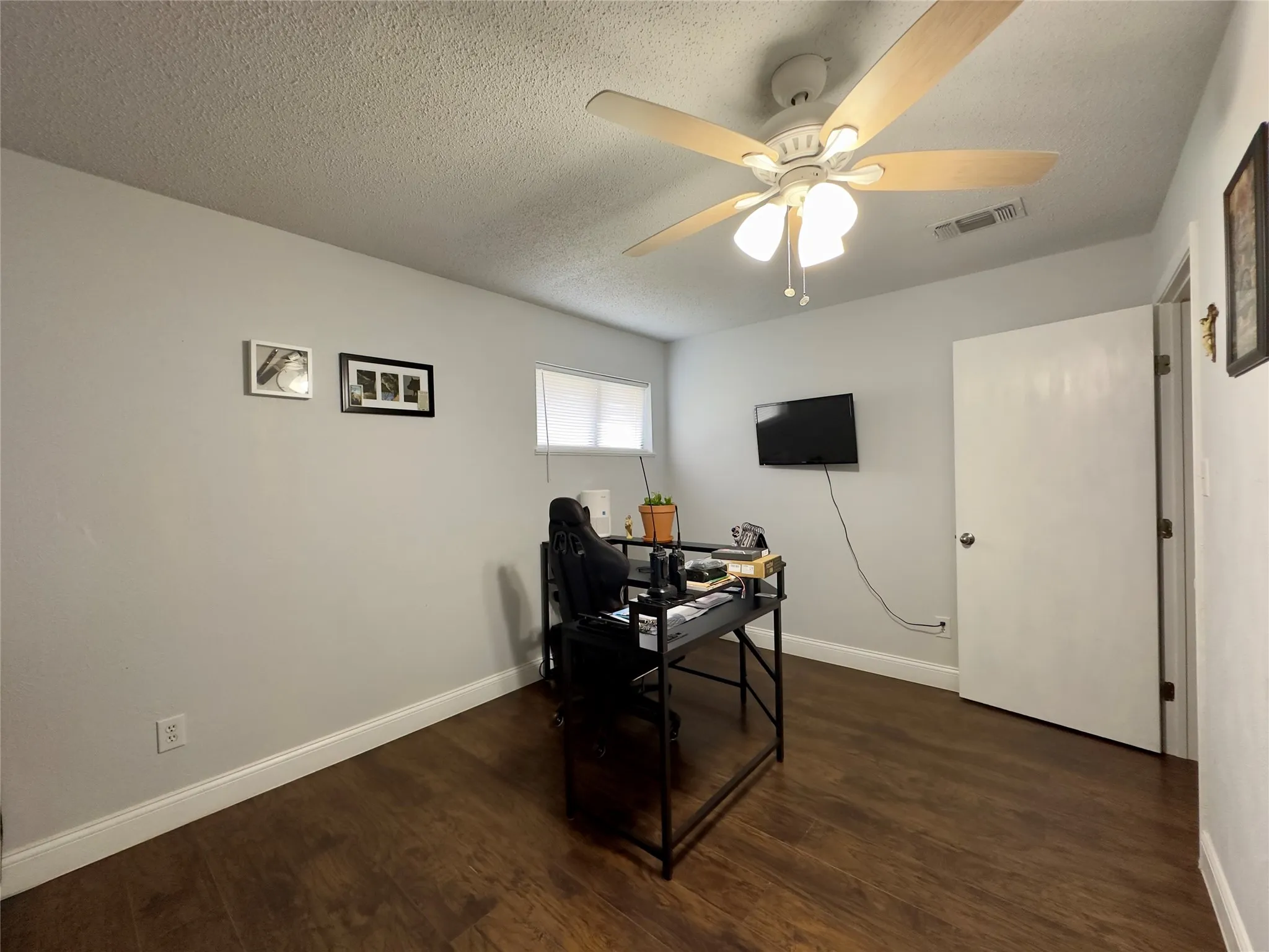 Wood-finish flooring, white painted walls, and a ceiling fan with integrated lighting