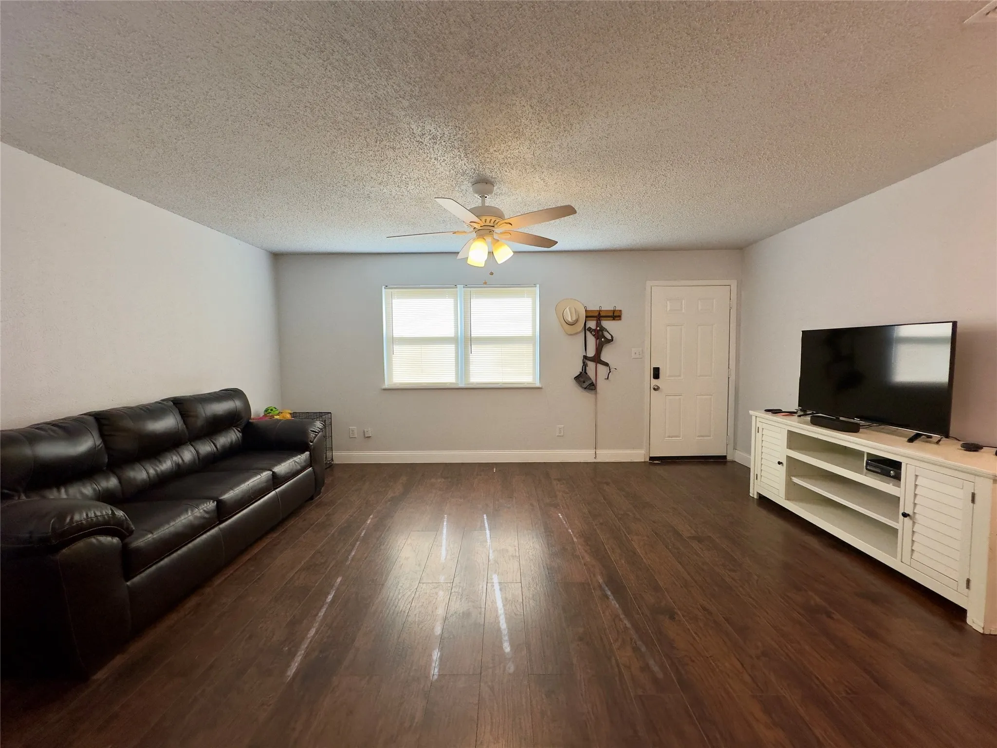 Wood-finish flooring throughout, light gray wall paint, and a ceiling fan with integrated lighting