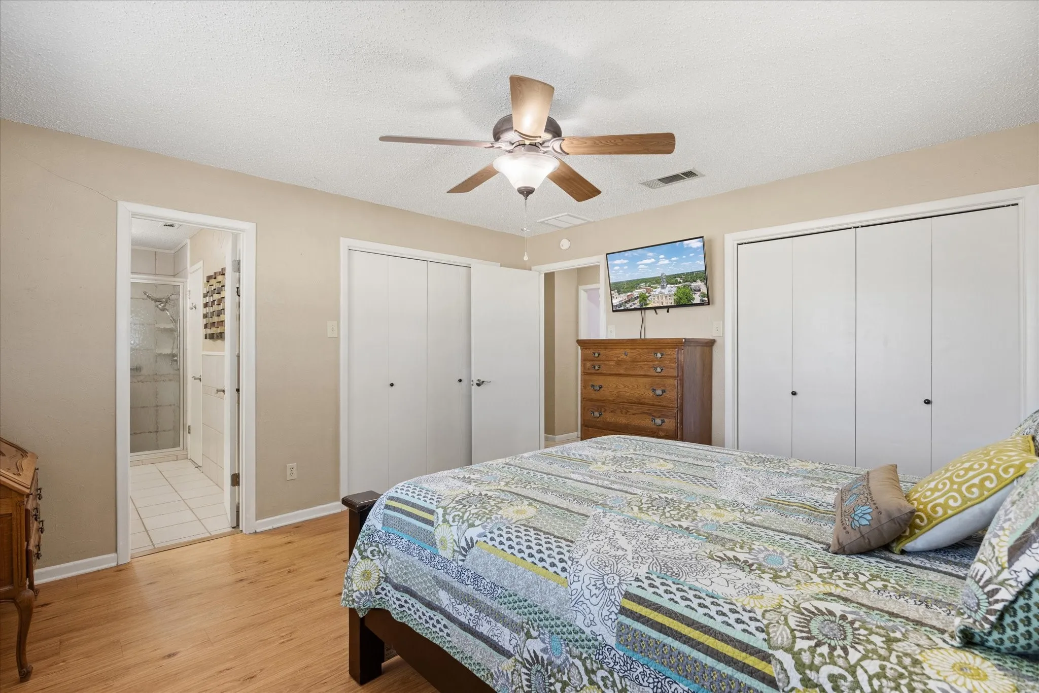 Wood-finish flooring, ceiling fan, and white bi-fold closet doors