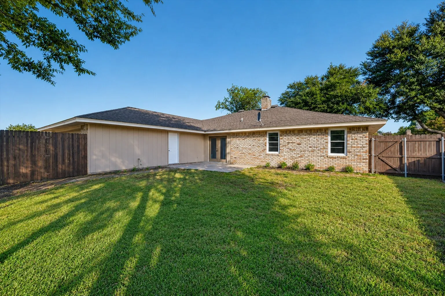 Expansive green lawn with a wood fence perimeter