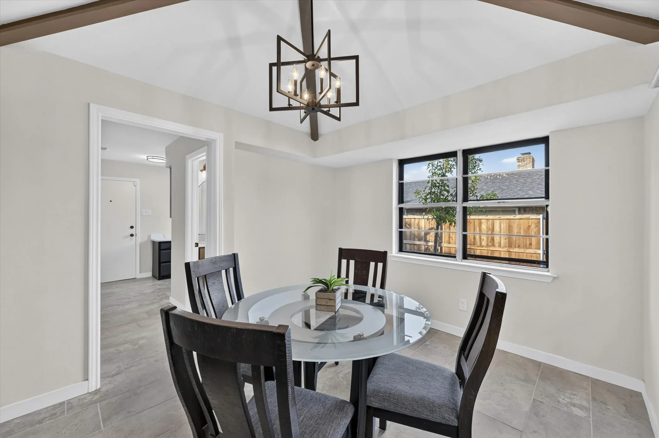Recessed windows with dark trim, ceiling with exposed beams, and a geometric-frame chandelier