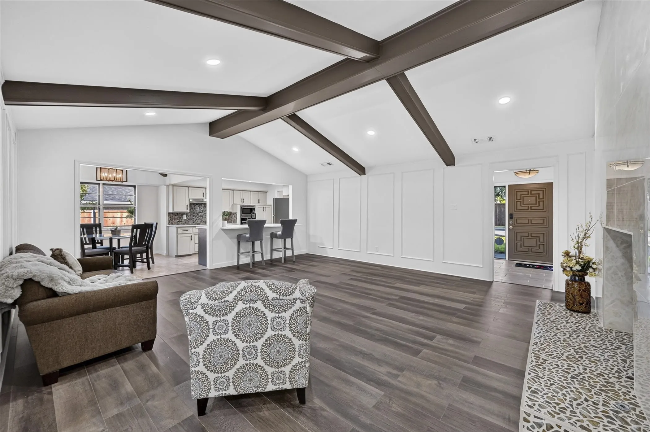 Vaulted ceiling with exposed beams, recessed lighting, wood-finish flooring, decorative wall molding, and a built-in fireplace hearth with mosaic tile