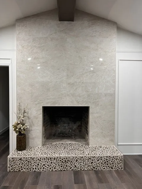 Fireplace featuring large format tile surround, brick firebox, and decorative tile hearth
