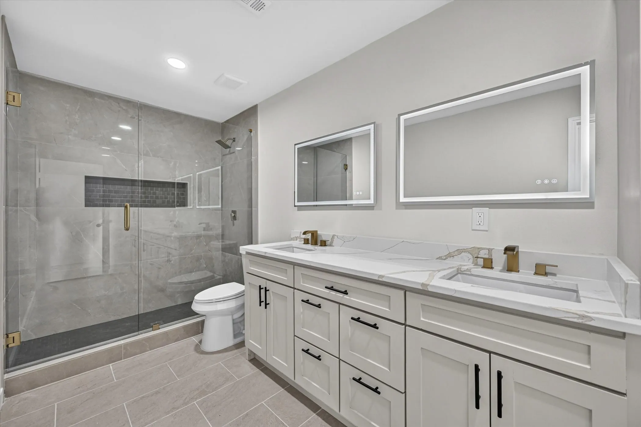 Dual vanity with white cabinetry, quartz countertop, and gold-finish fixtures