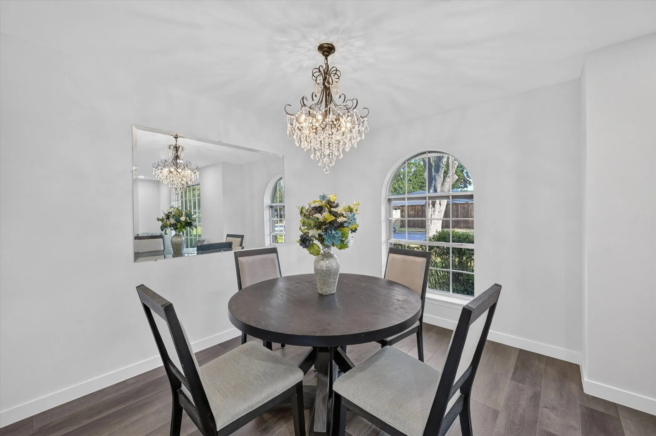 Crystal chandelier, arched window, wood-finish flooring, built-in wall mirror, white wall finishes