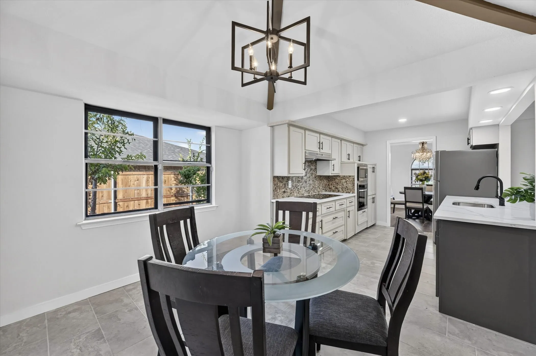 Kitchen with white cabinetry, built-in appliances, stone backsplash, and contrasting island with a white countertop
