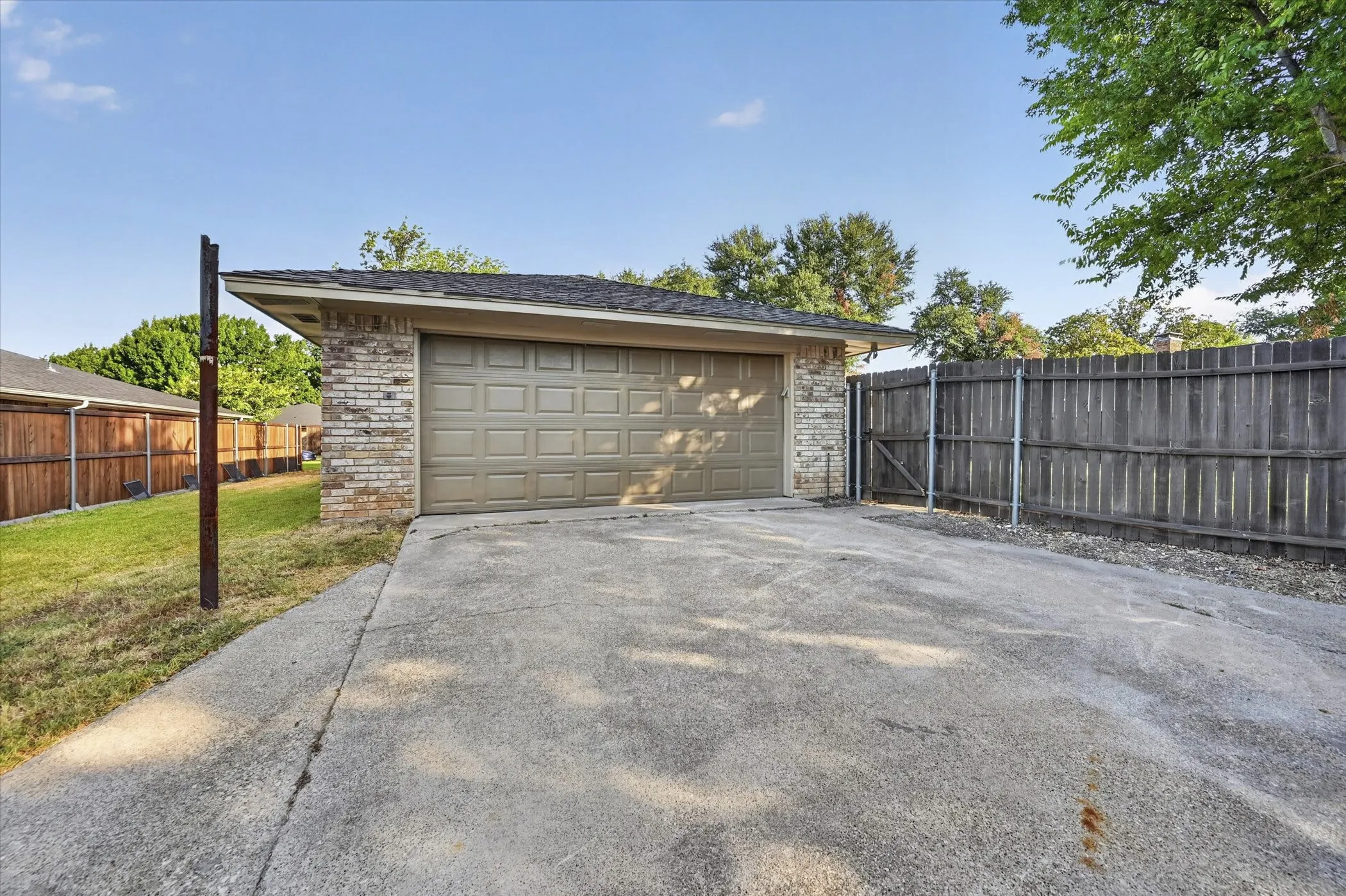 Attached two-car garage with a panel door, brick facade, and concrete driveway