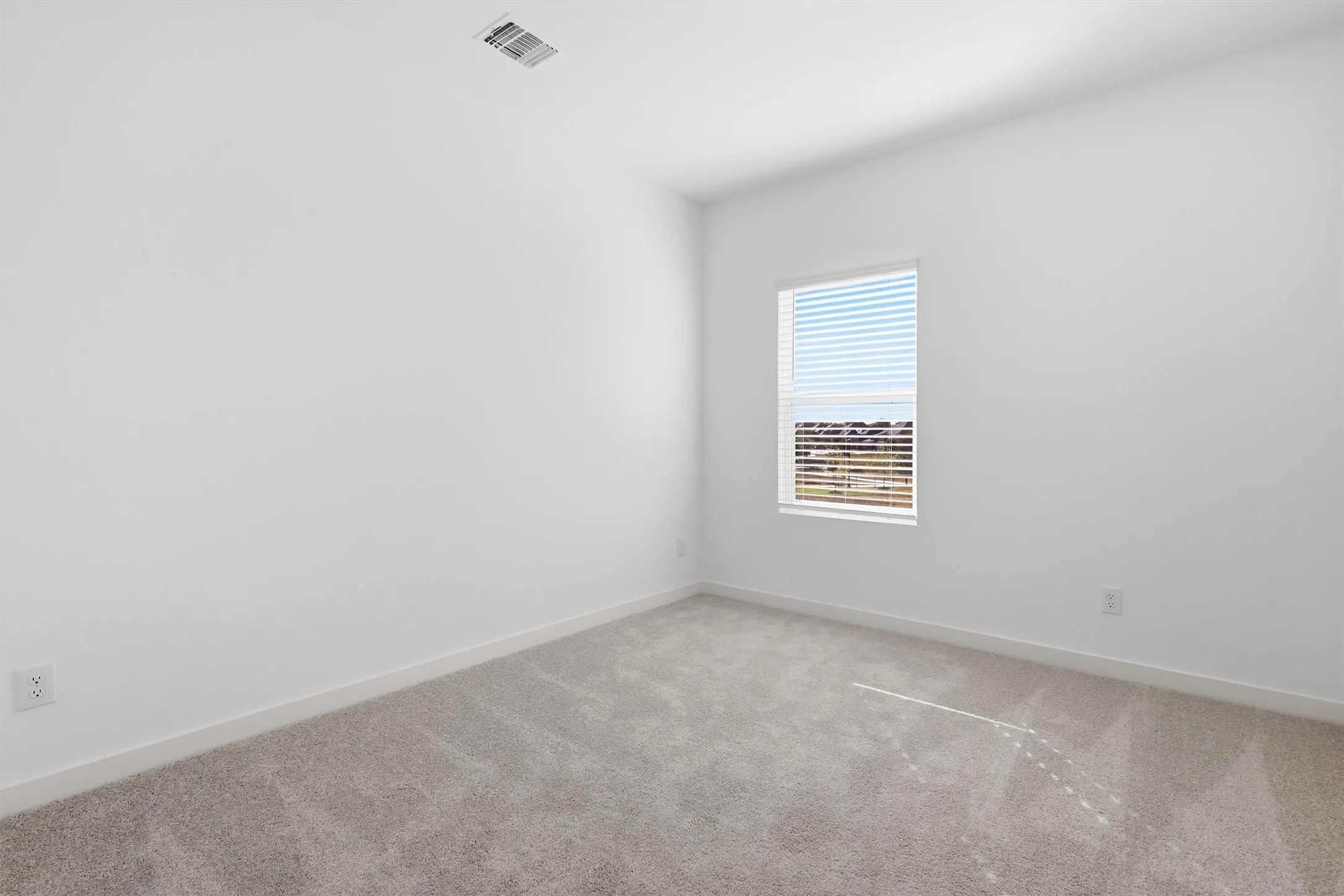 Recessed window with horizontal blinds, light gray wall-to-wall carpeting, and white painted walls