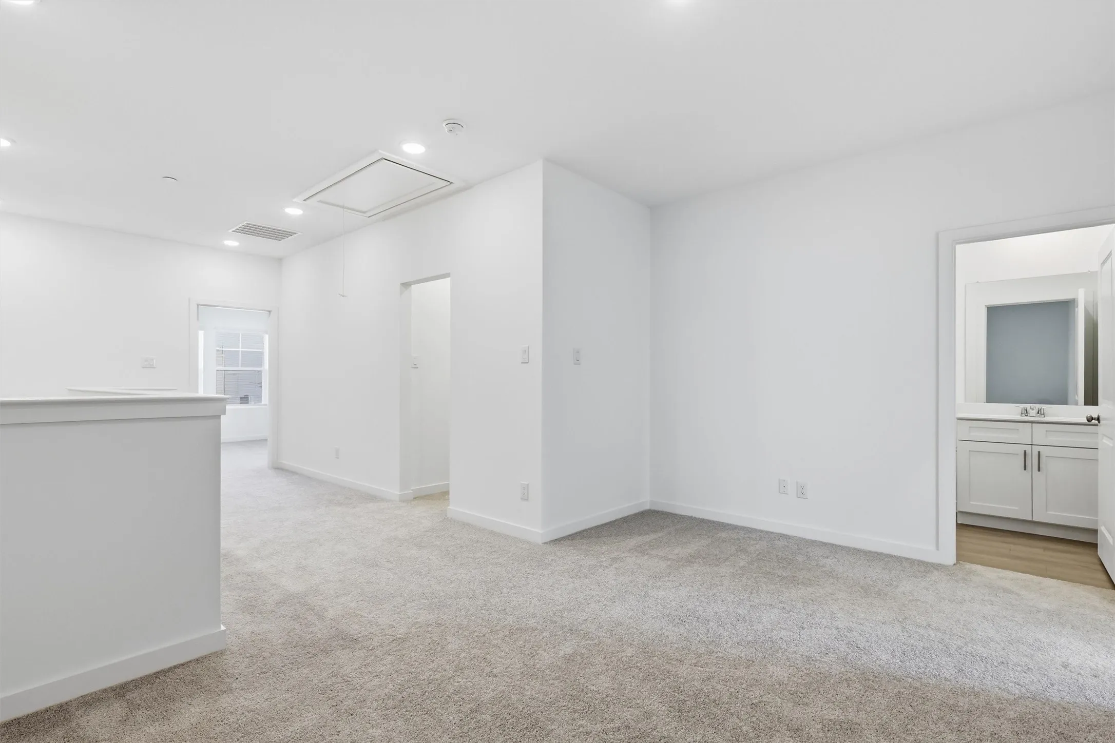 Recessed lighting, carpet flooring, a white window frame, and a white vanity with a rectangular sink