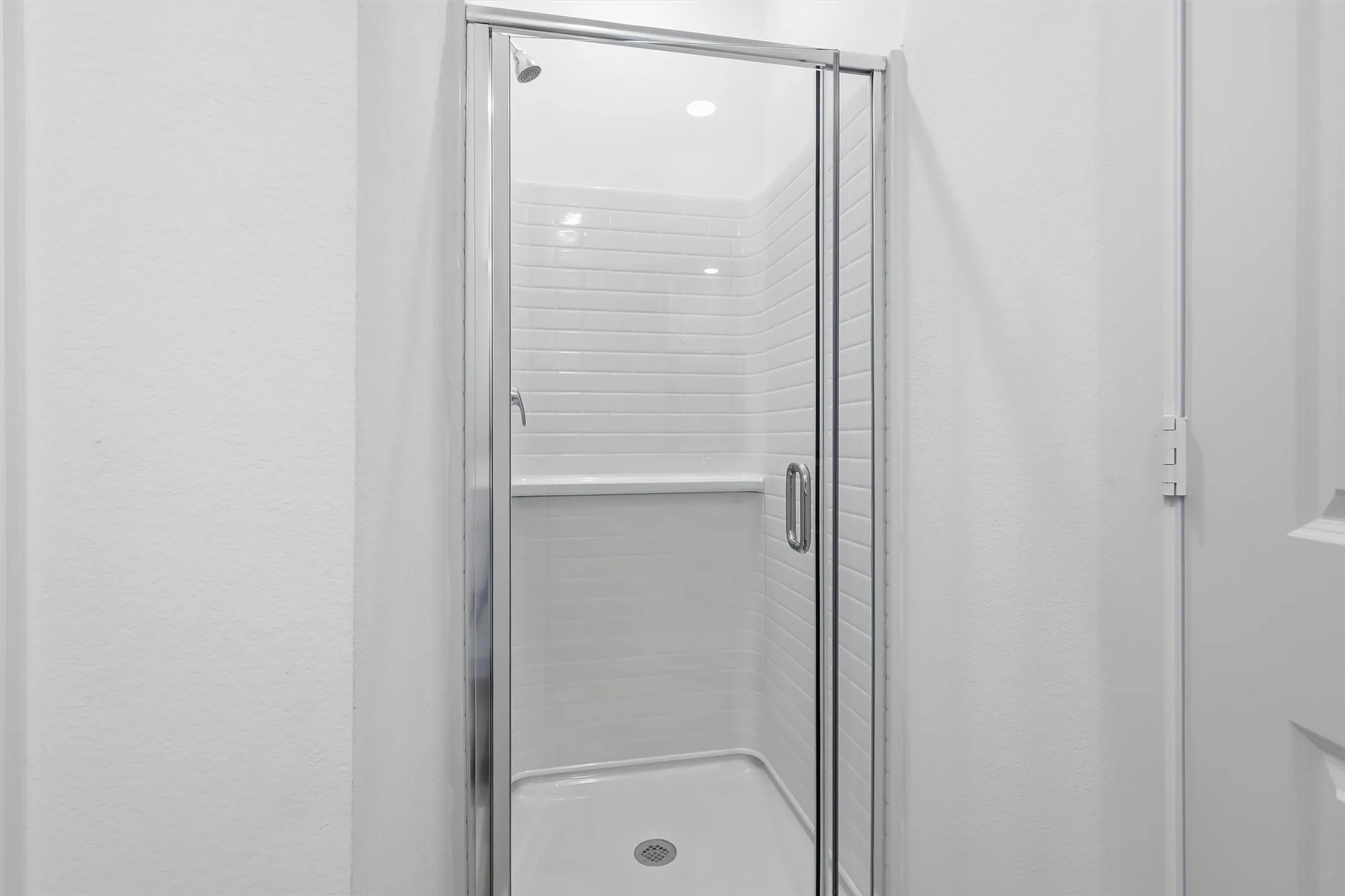 Walk-in shower with clear glass enclosure and chrome hardware