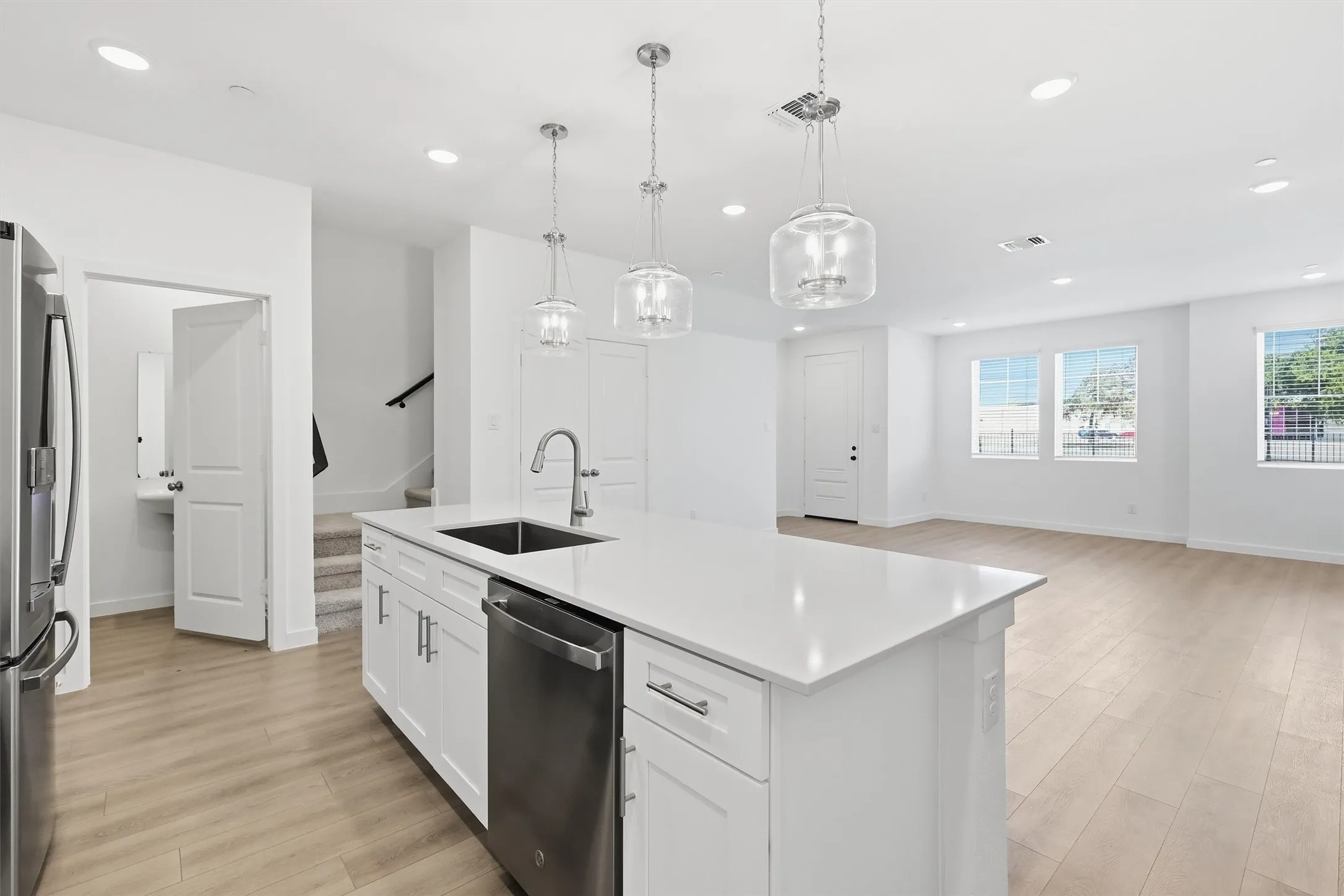 Kitchen island with white cabinetry, stainless steel appliances, and a solid surface countertop