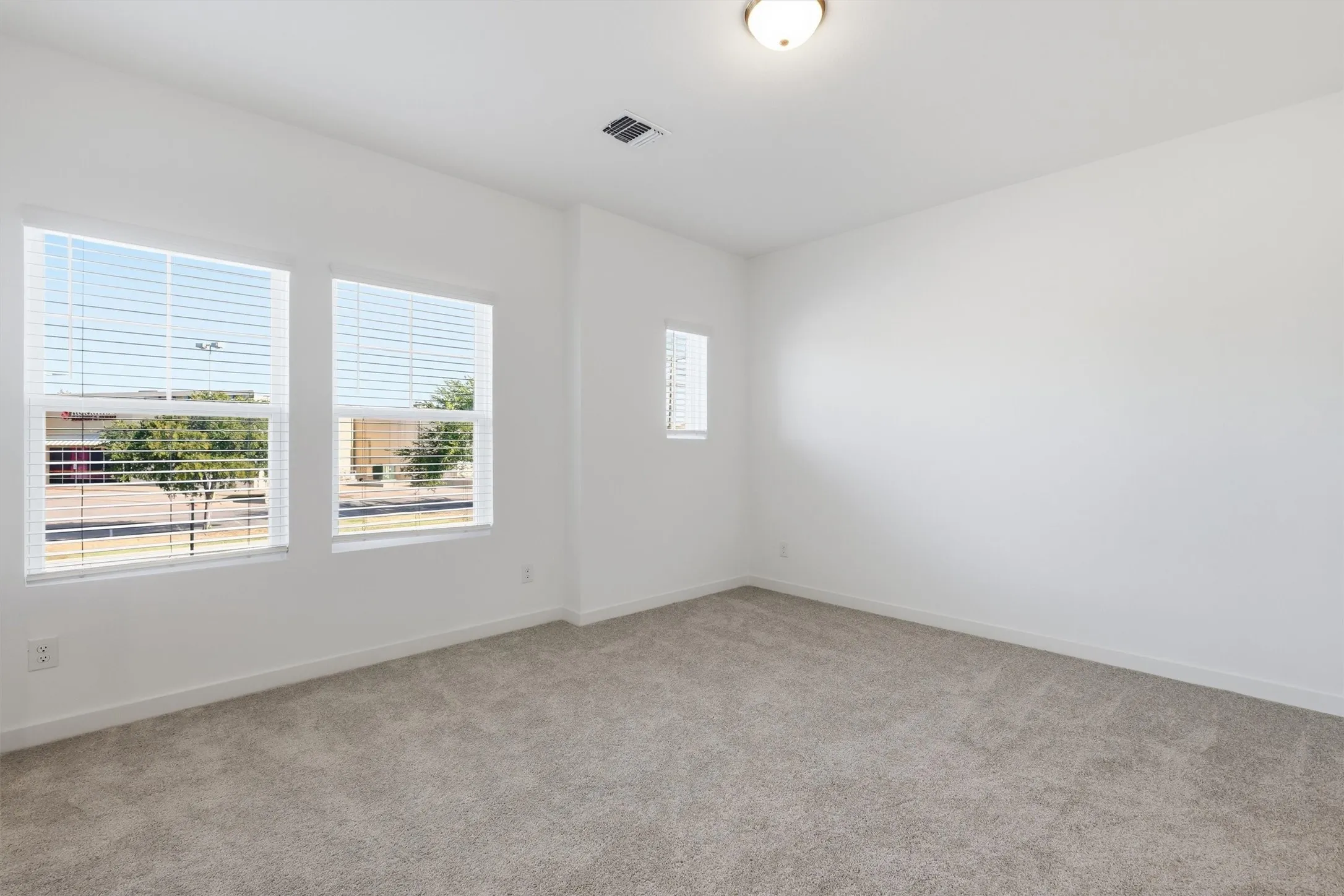 Recessed ceiling light fixture, white walls, and light-colored carpet flooring