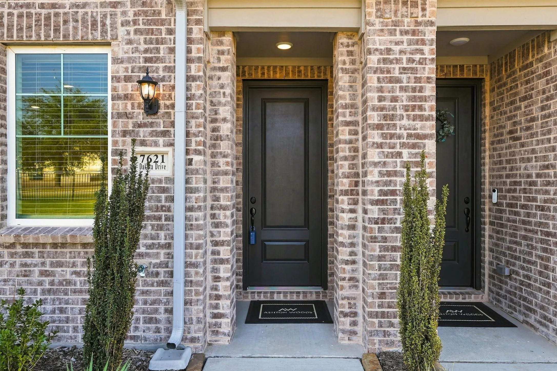Brick exterior with a prominent entrance, white frame window, and outdoor wall sconce