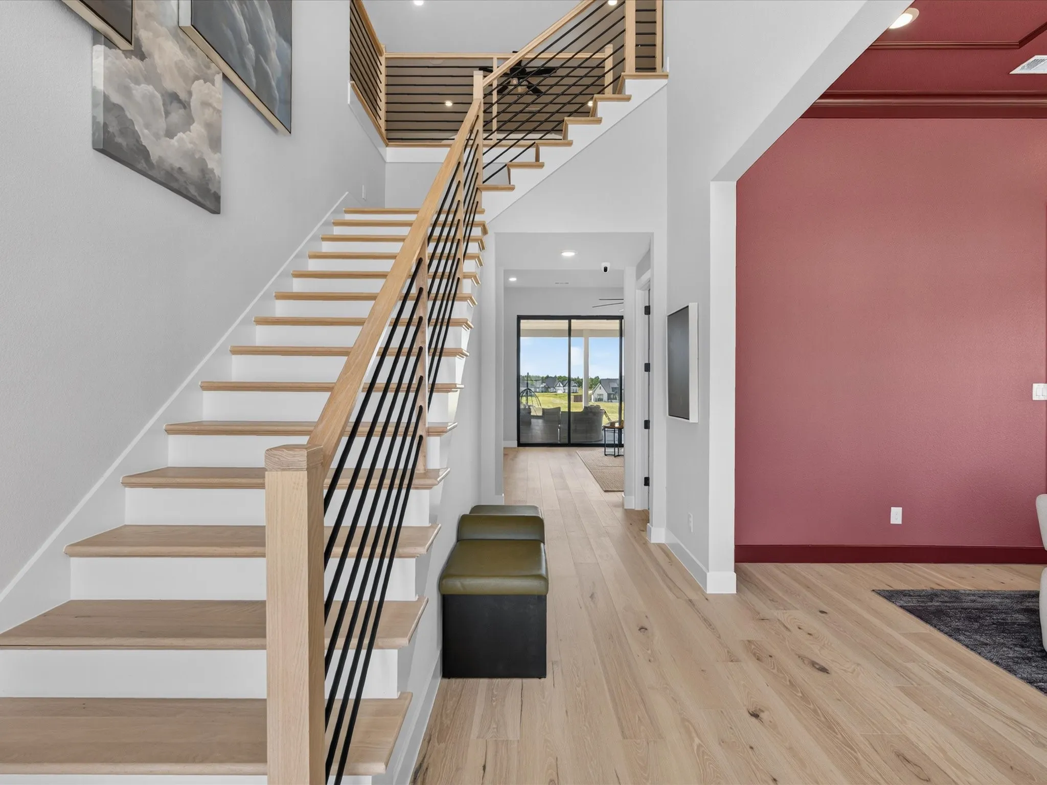 Two-story staircase with light wood-finish treads and black metal balusters