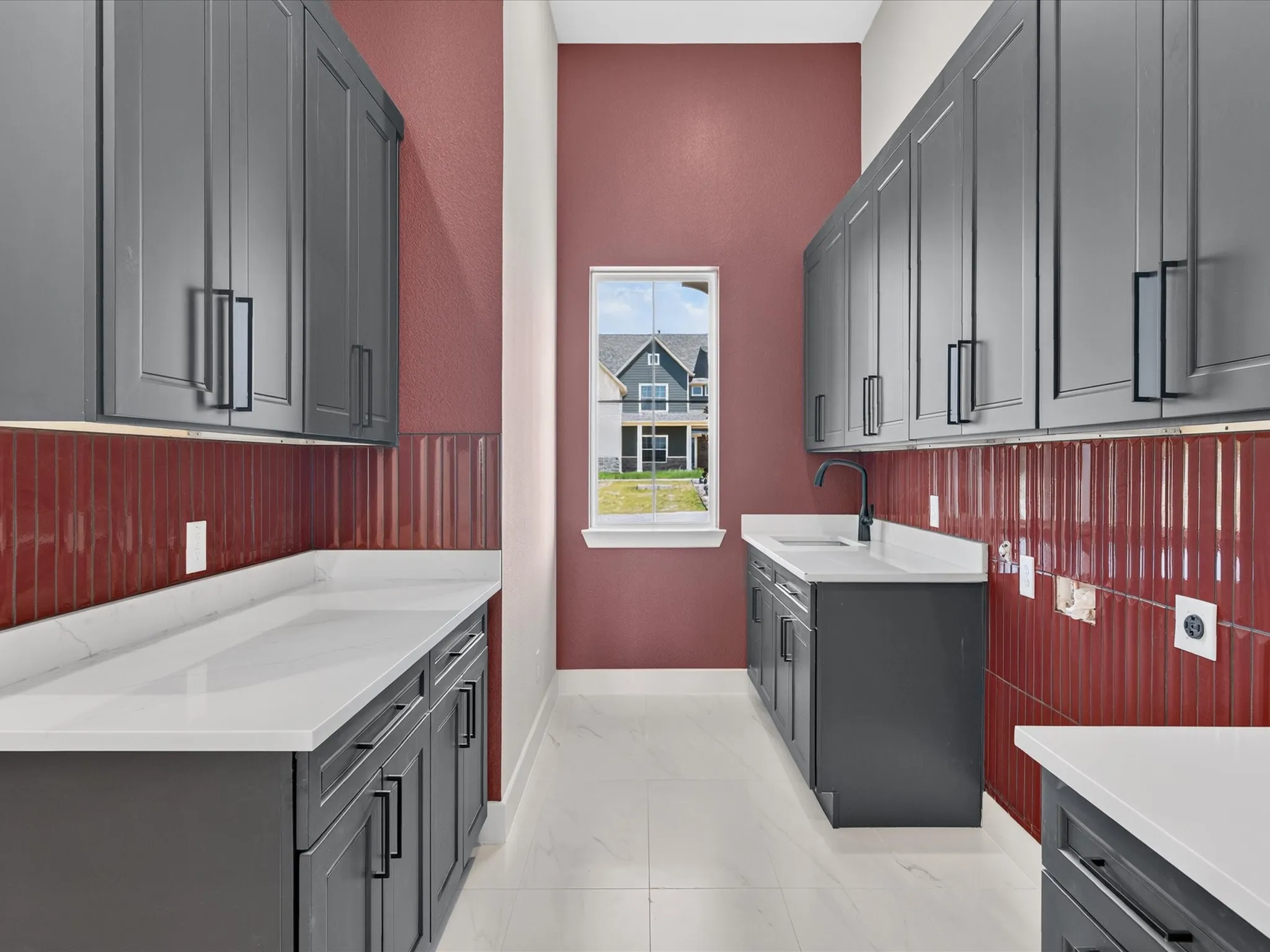 Extended upper cabinetry with black hardware, white countertops, deep red vertical tile backsplash, and a black sink faucet