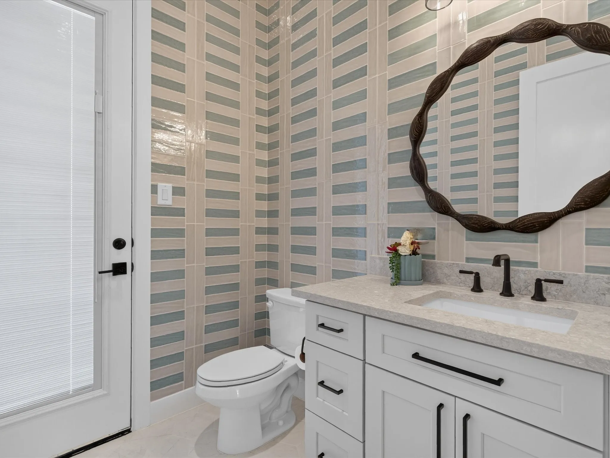 Powder room featuring a single vanity with stone countertop, integrated sink, and matte black fixtures