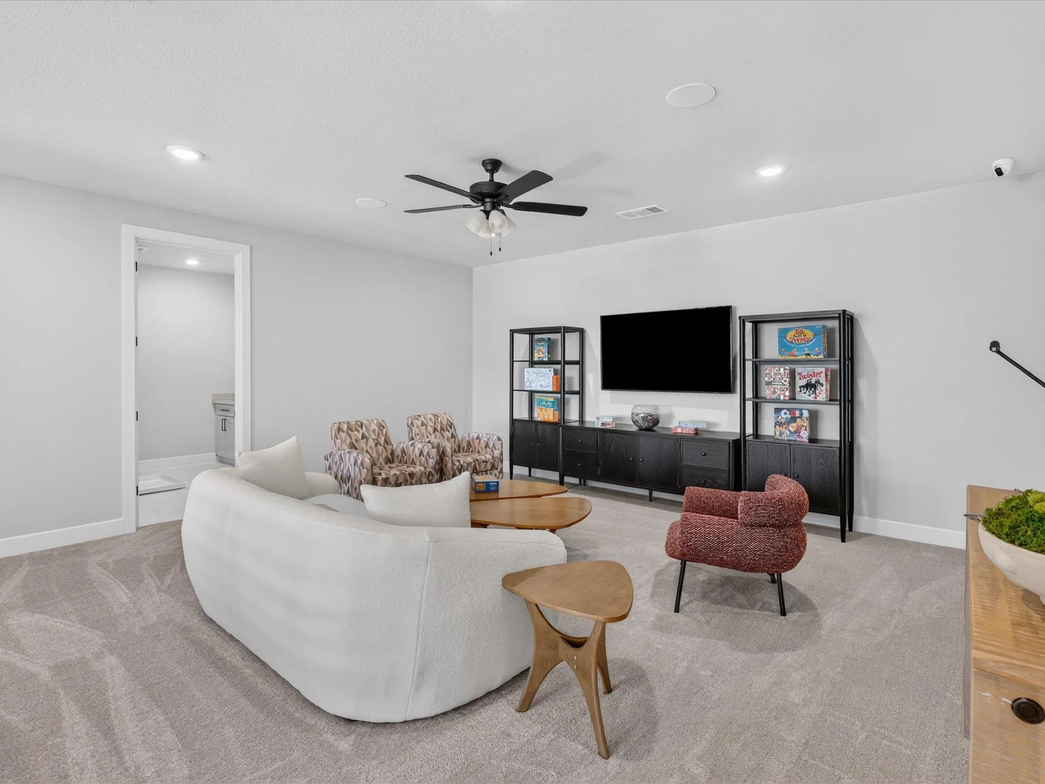 Recessed lighting, ceiling fan, carpet flooring, built-in shelving, and wall-mounted television
