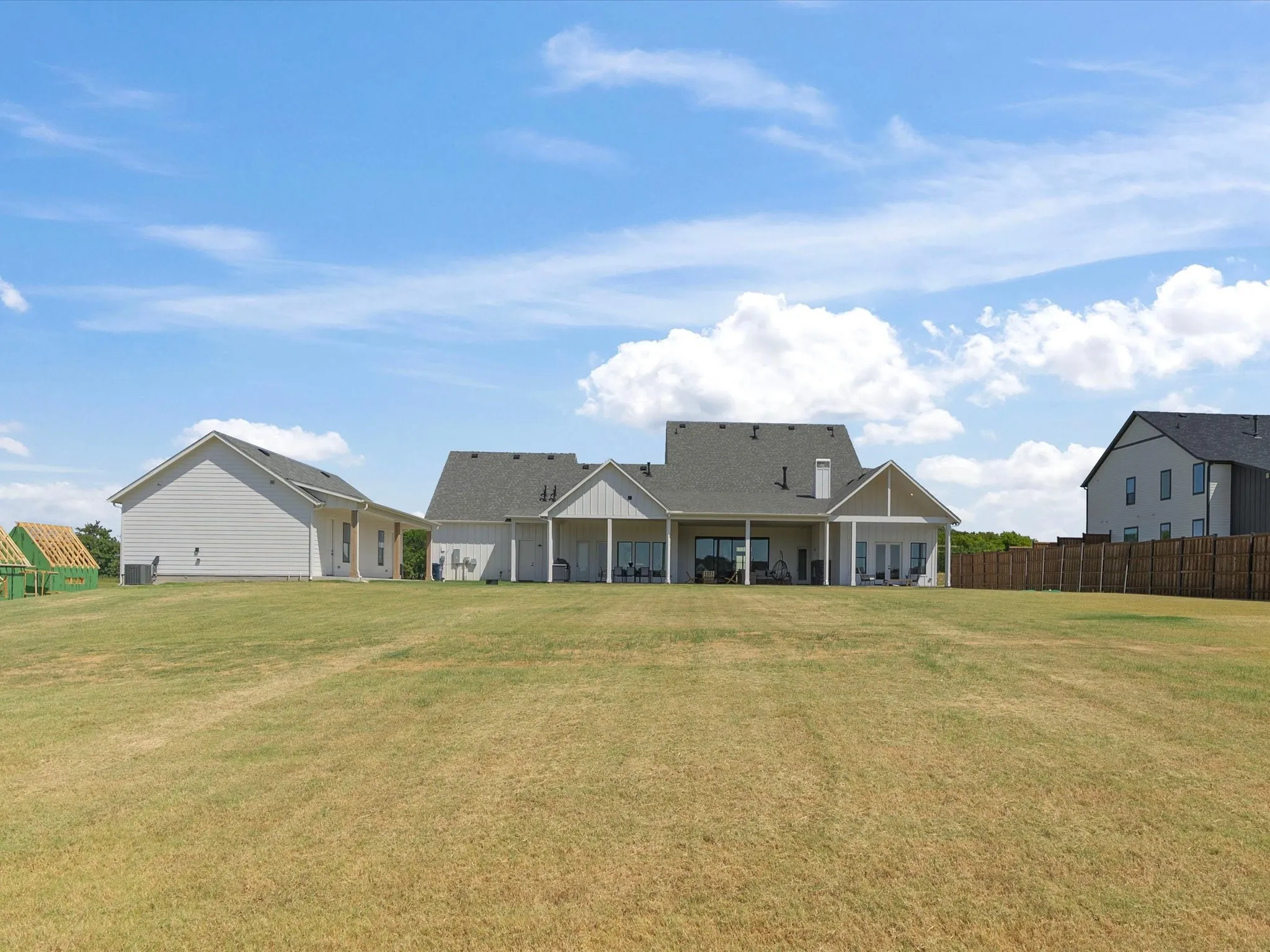 Expansive rear yard with a large grassy area, covered patio, and attached garage structure