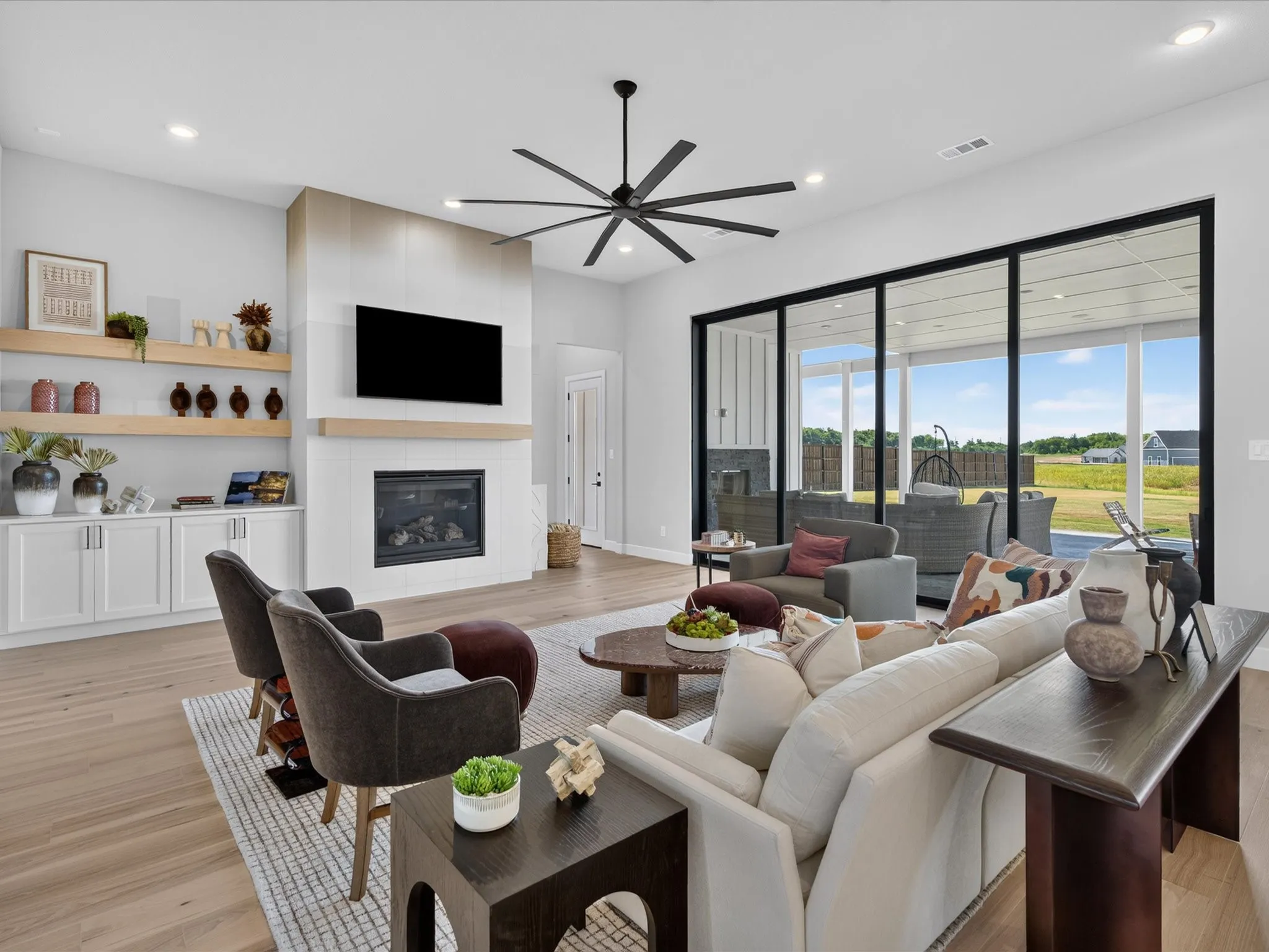 Open-concept living area featuring wood-finish flooring, a contemporary fireplace with mantel, and built-in cabinetry with floating shelves
