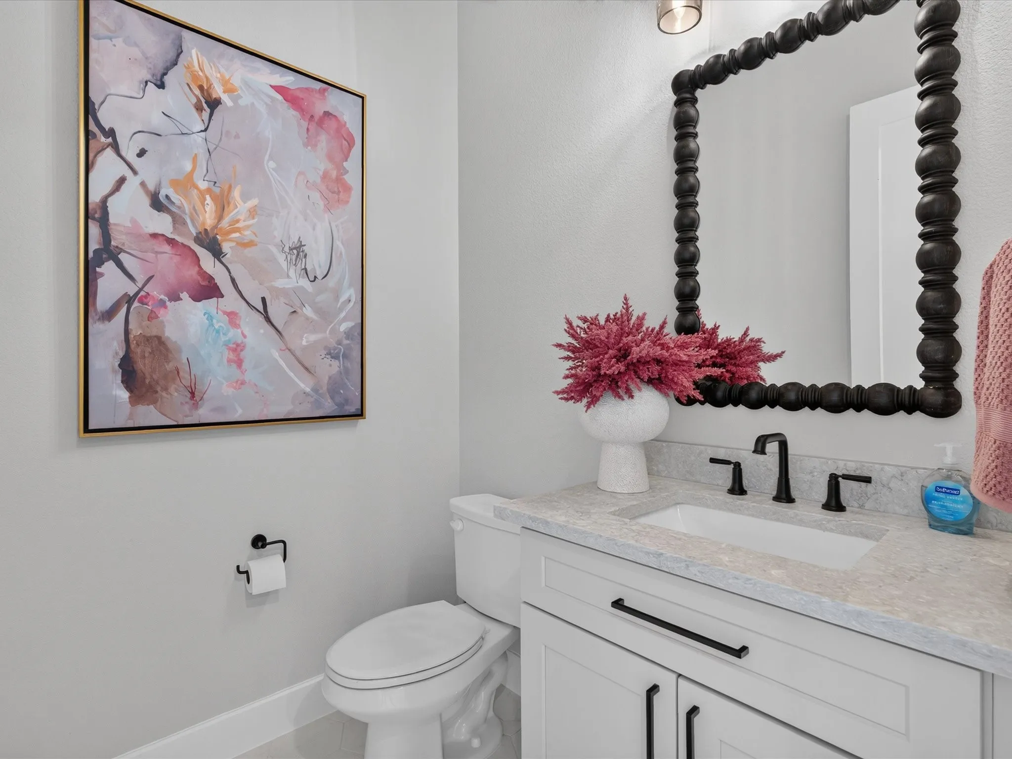 White vanity with black hardware, integrated sink, and light-toned countertop