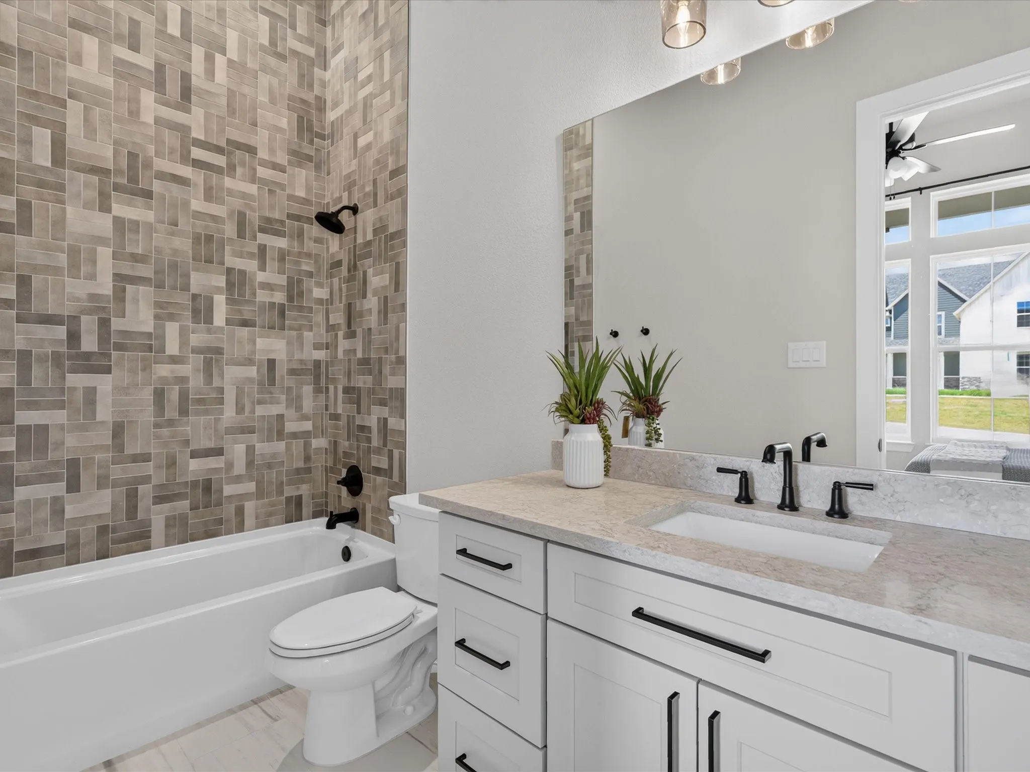 White vanity with dark hardware, undermount sink, light-toned countertop, and full-width mirror